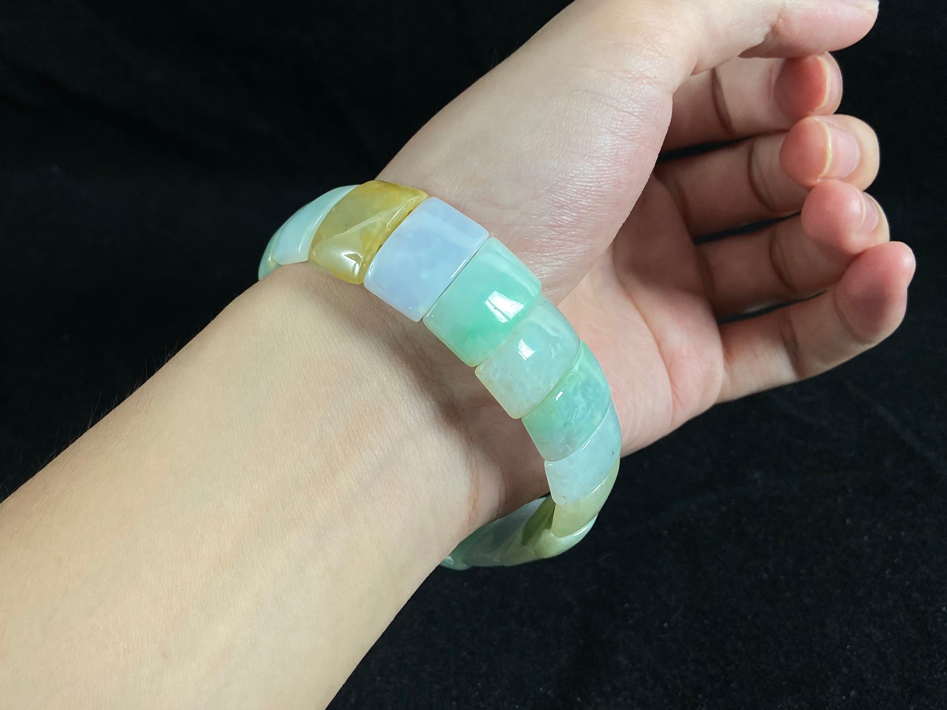 A rectangular jade bangle featuring an earthy palette of green, cream, purple and brown.