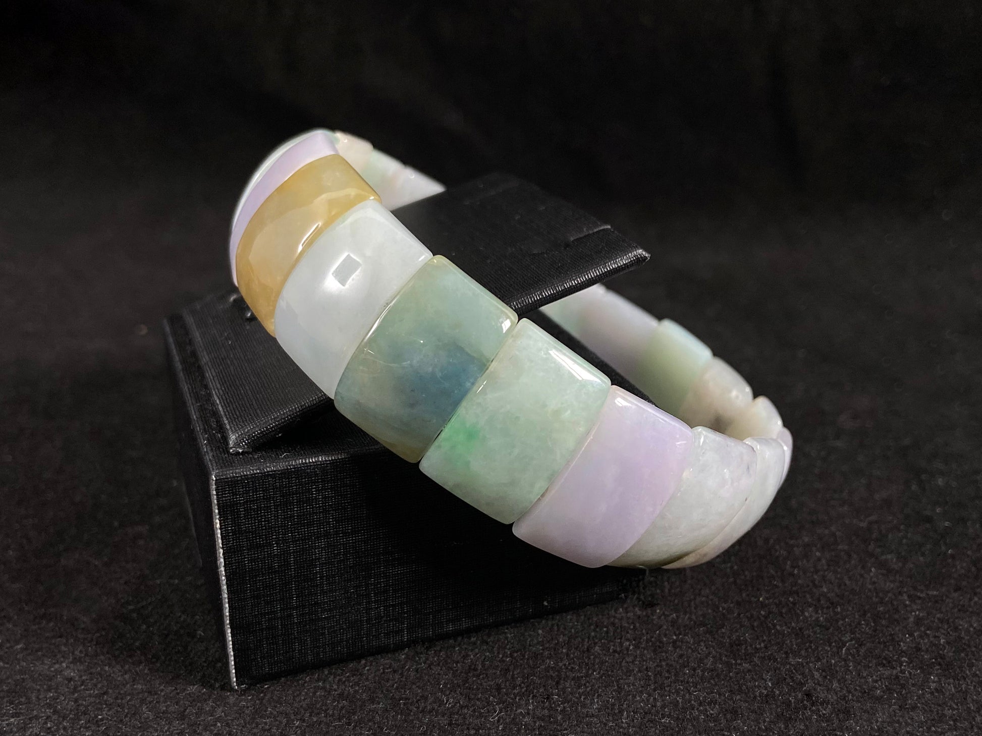 A rectangular jade bangle featuring an earthy palette of green, cream, purple and brown.