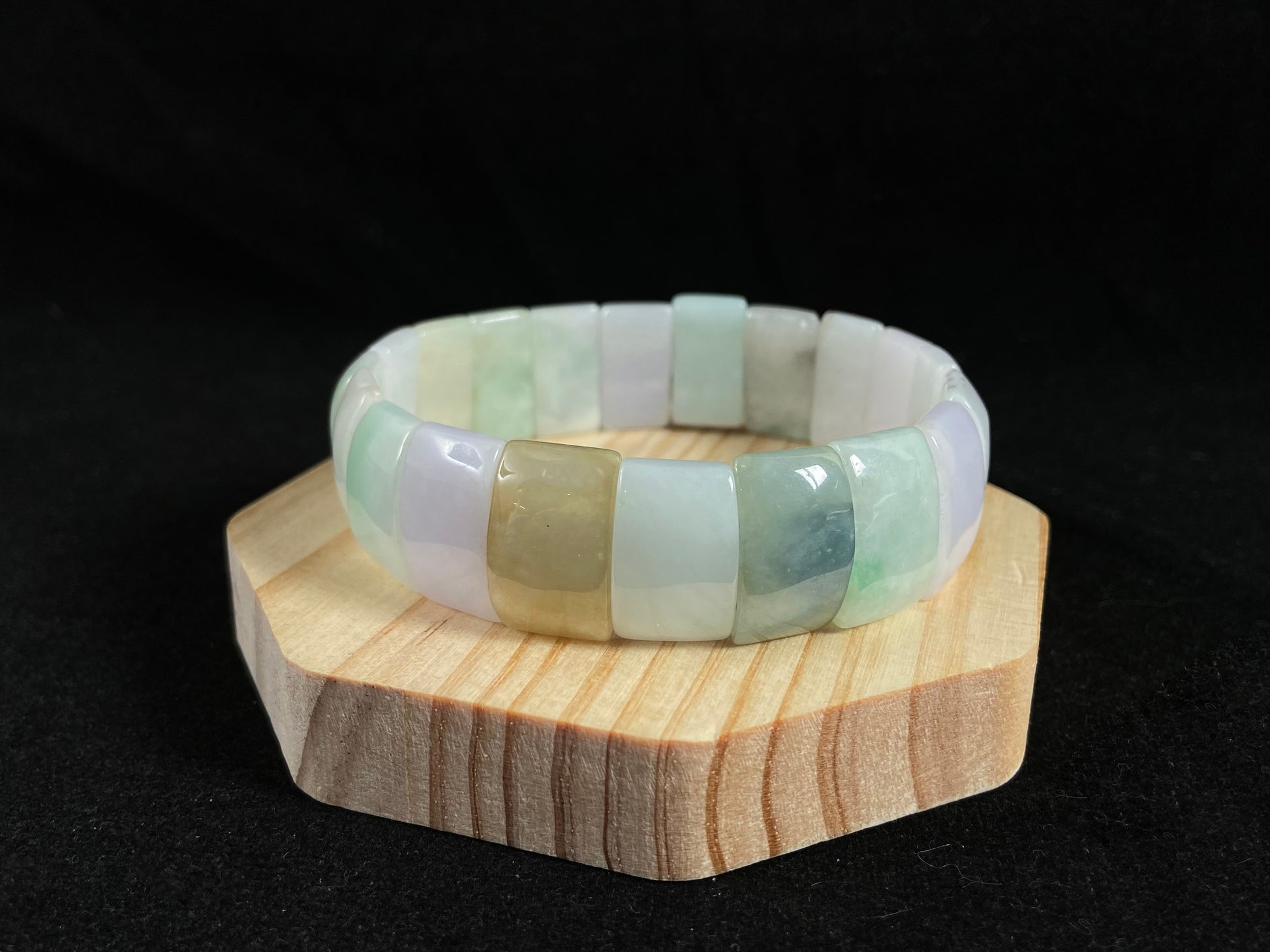 A rectangular jade bangle featuring an earthy palette of green, cream, purple and brown.