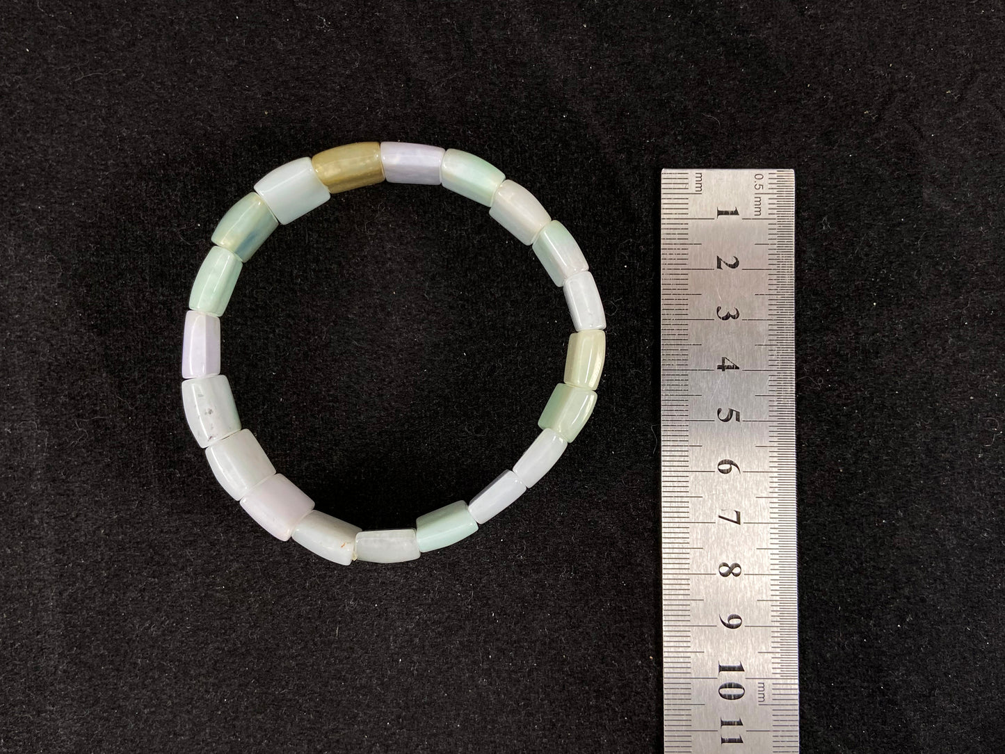 A rectangular jade bangle featuring an earthy palette of green, cream, purple and brown.