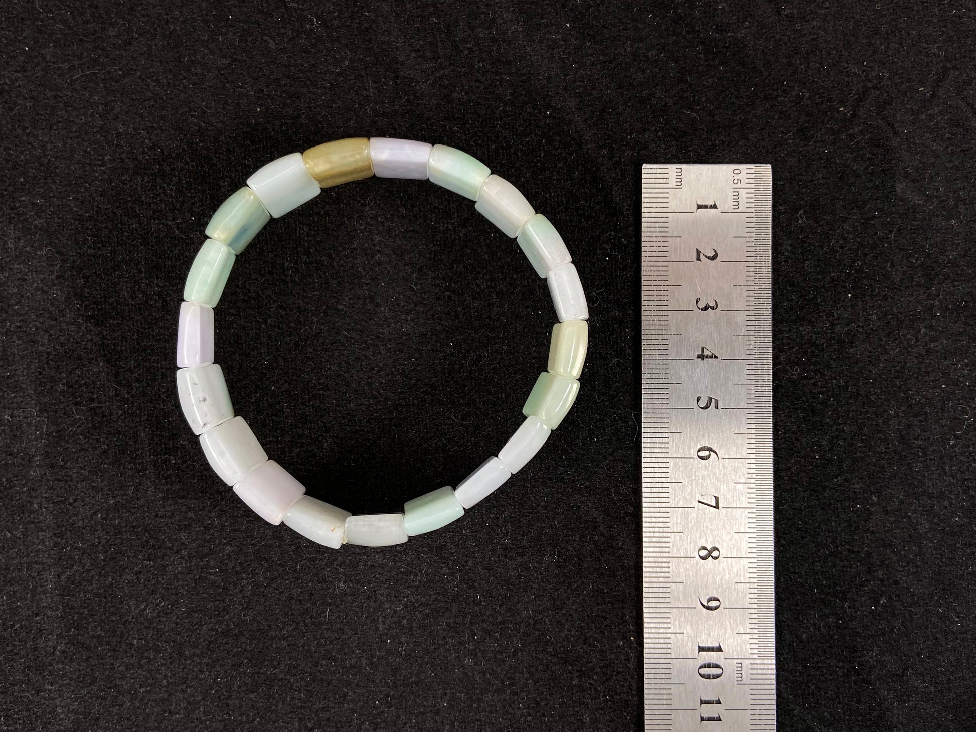 A rectangular jade bangle featuring an earthy palette of green, cream, purple and brown.