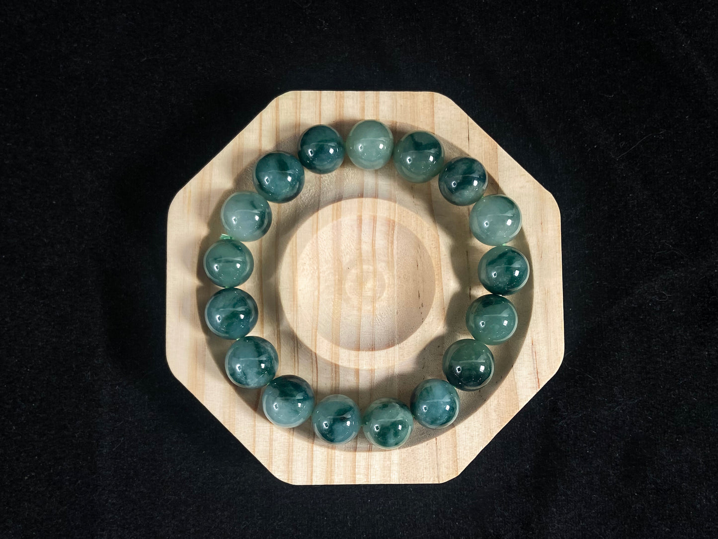 This jadeite bead strand has beads of the same size each translucent one with a soft white green base, dotted with dark green.