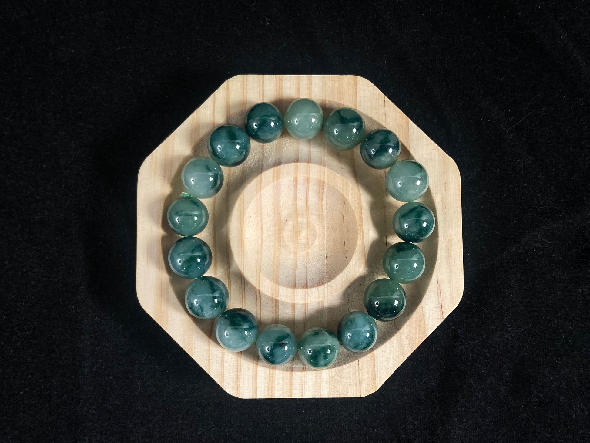 This jadeite bead strand has beads of the same size each translucent one with a soft white green base, dotted with dark green.