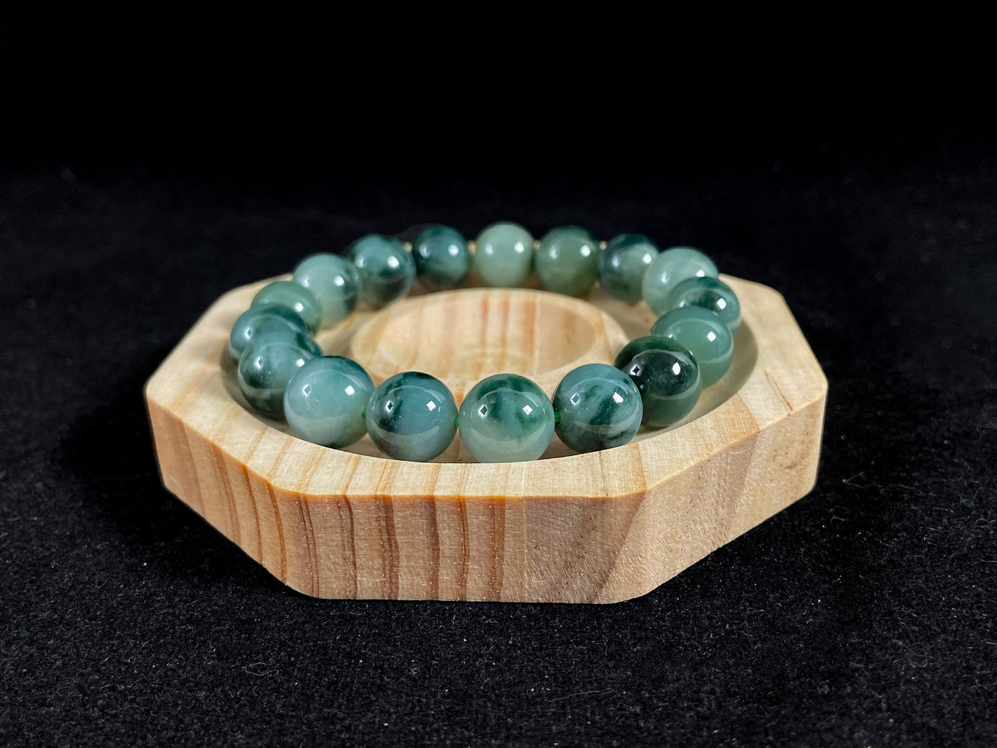 This jadeite bead strand has beads of the same size each translucent one with a soft white green base, dotted with dark green.