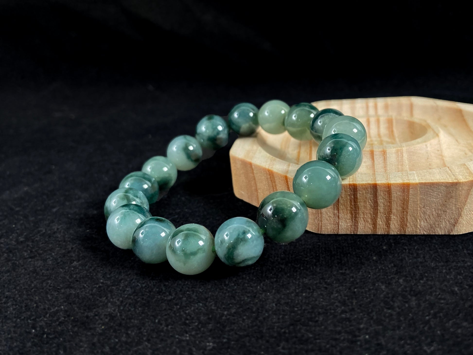 This jadeite bead strand has beads of the same size each translucent one with a soft white green base, dotted with dark green.