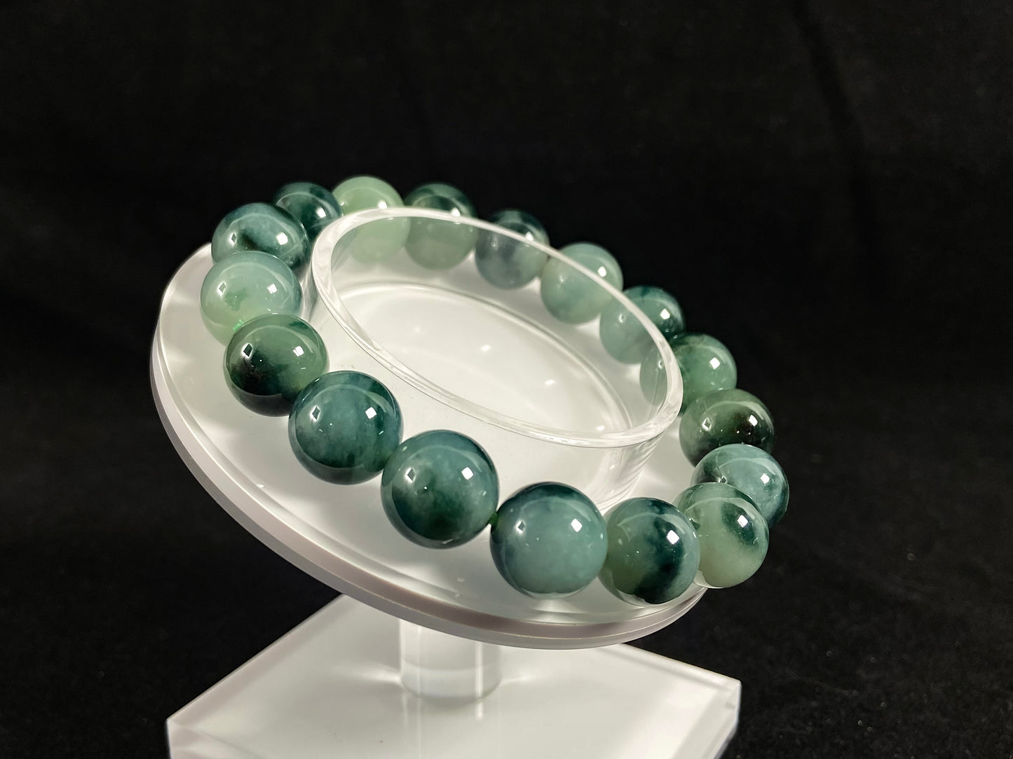 This jadeite bead strand has beads of the same size each translucent one with a soft white green base, dotted with dark green.