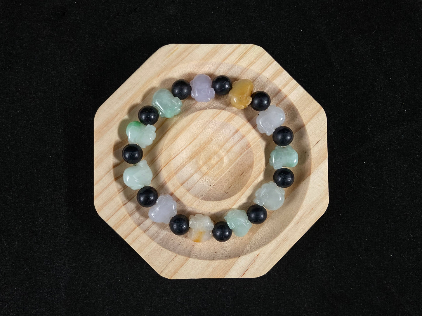 A jade bead strand featuring purple, pale green, brown, and translucent white pig charms.