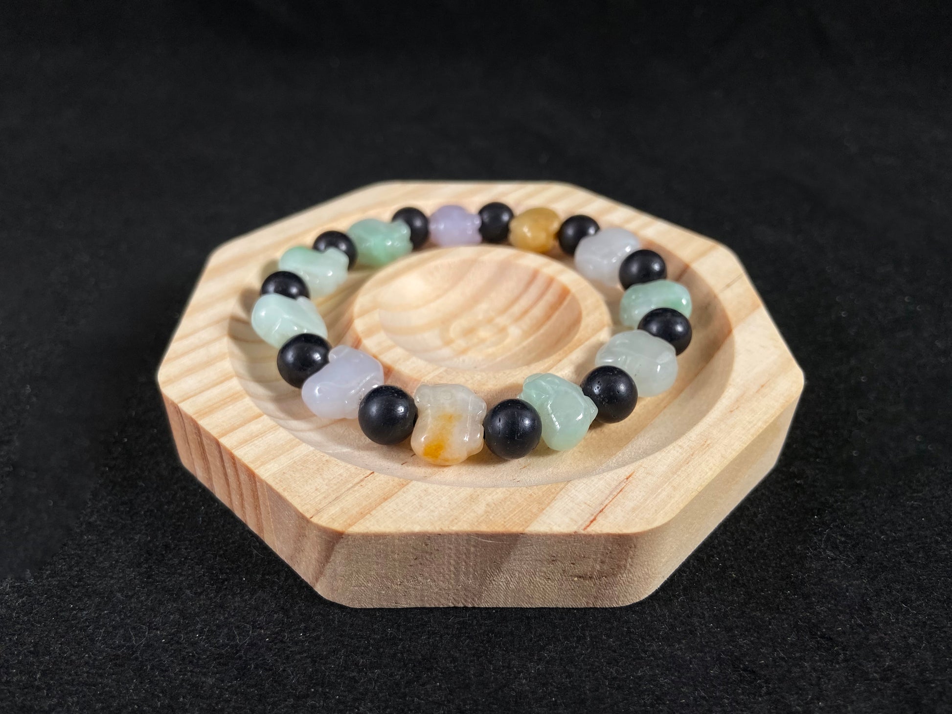 A jade bead strand featuring purple, pale green, brown, and translucent white pig charms.