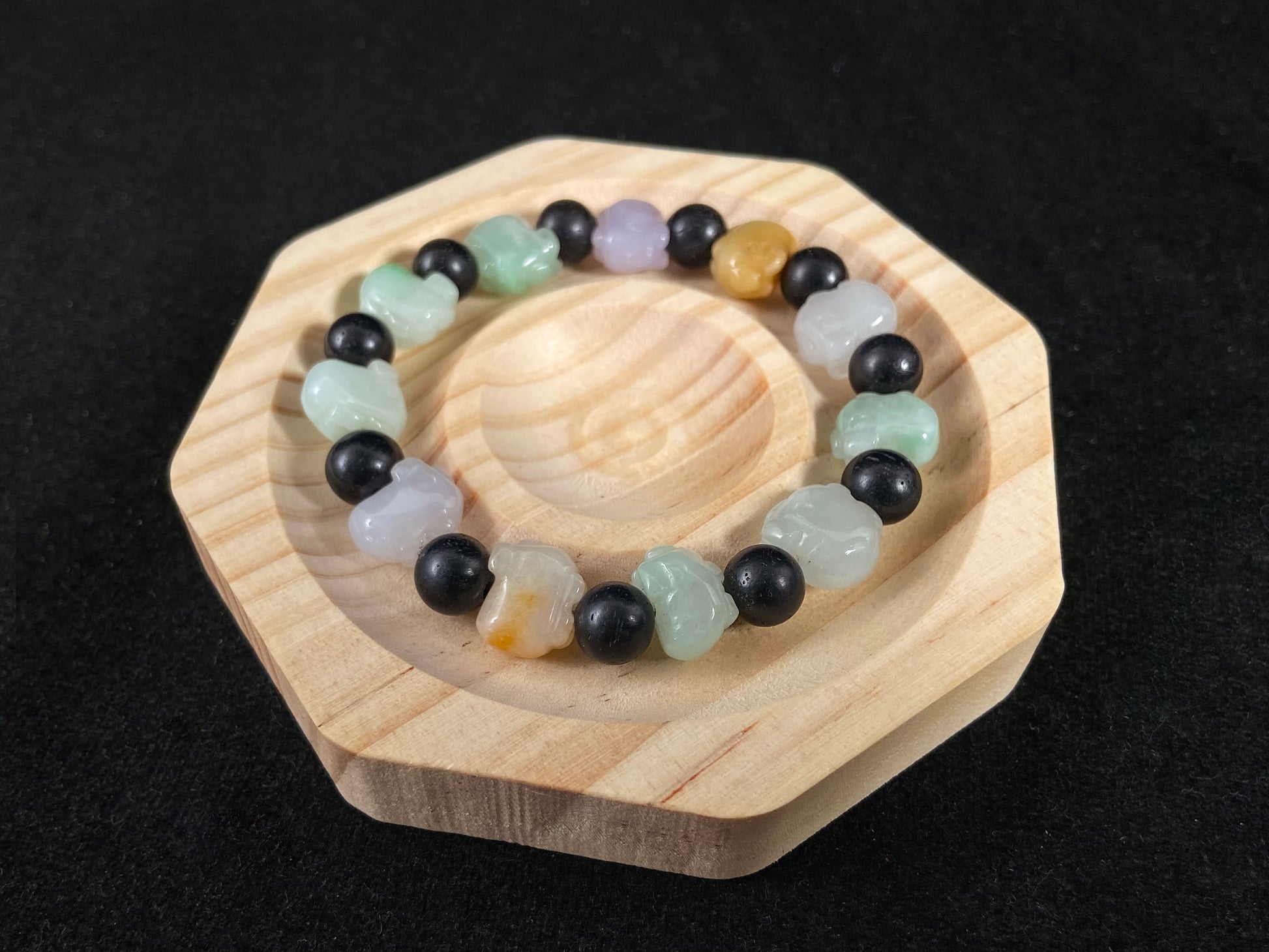 A jade bead strand featuring purple, pale green, brown, and translucent white pig charms.