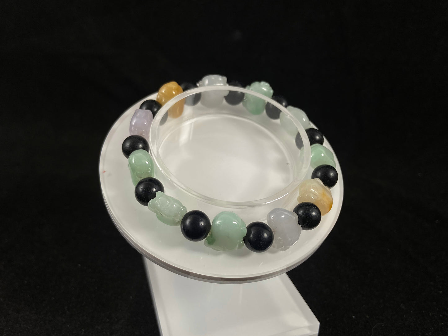 A jade bead strand featuring purple, pale green, brown, and translucent white pig charms.