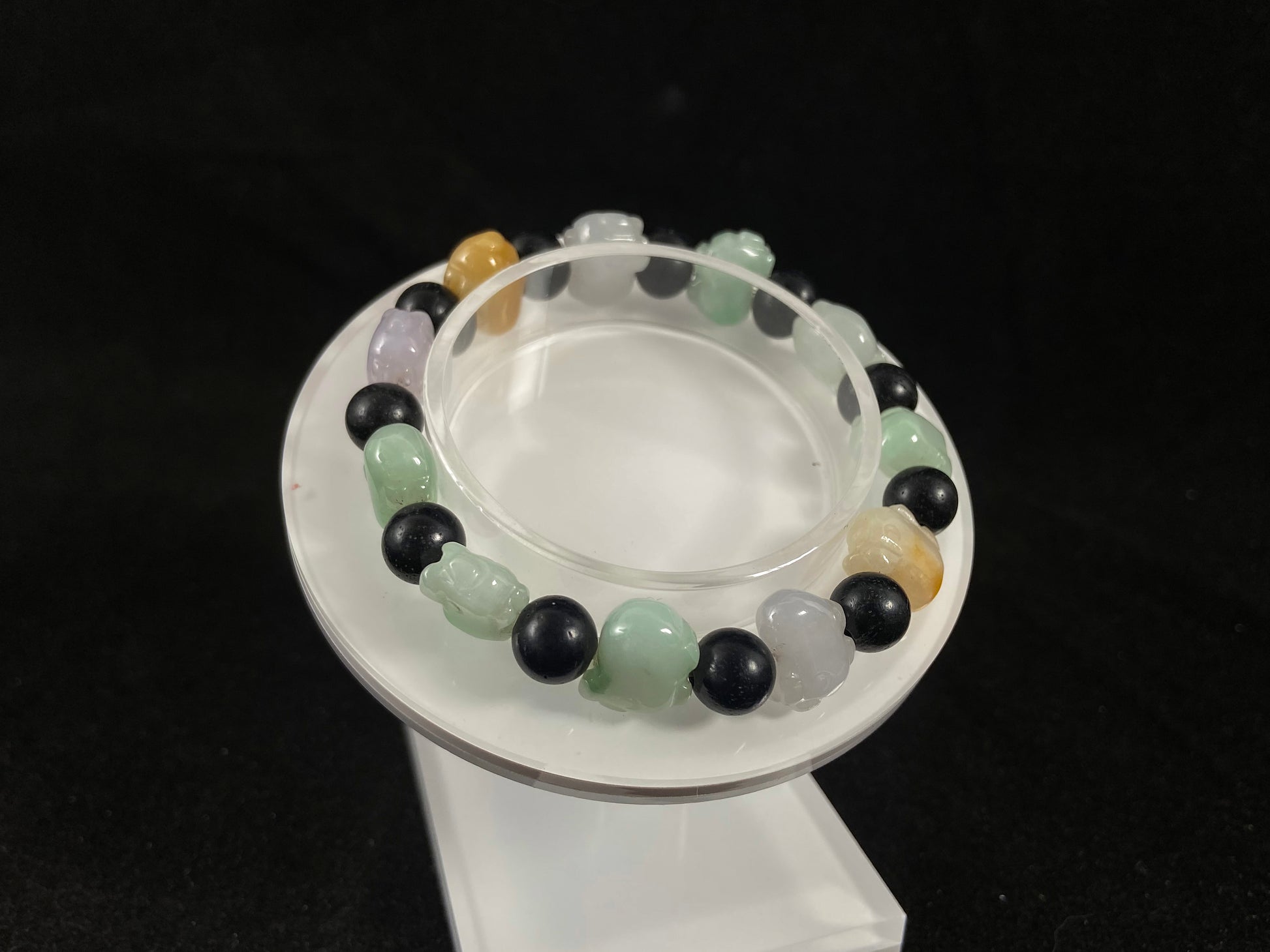 A jade bead strand featuring purple, pale green, brown, and translucent white pig charms.