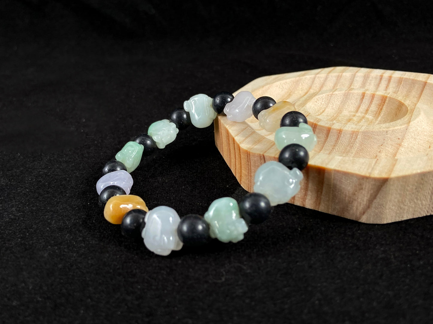 A jade bead strand featuring purple, pale green, brown, and translucent white pig charms.