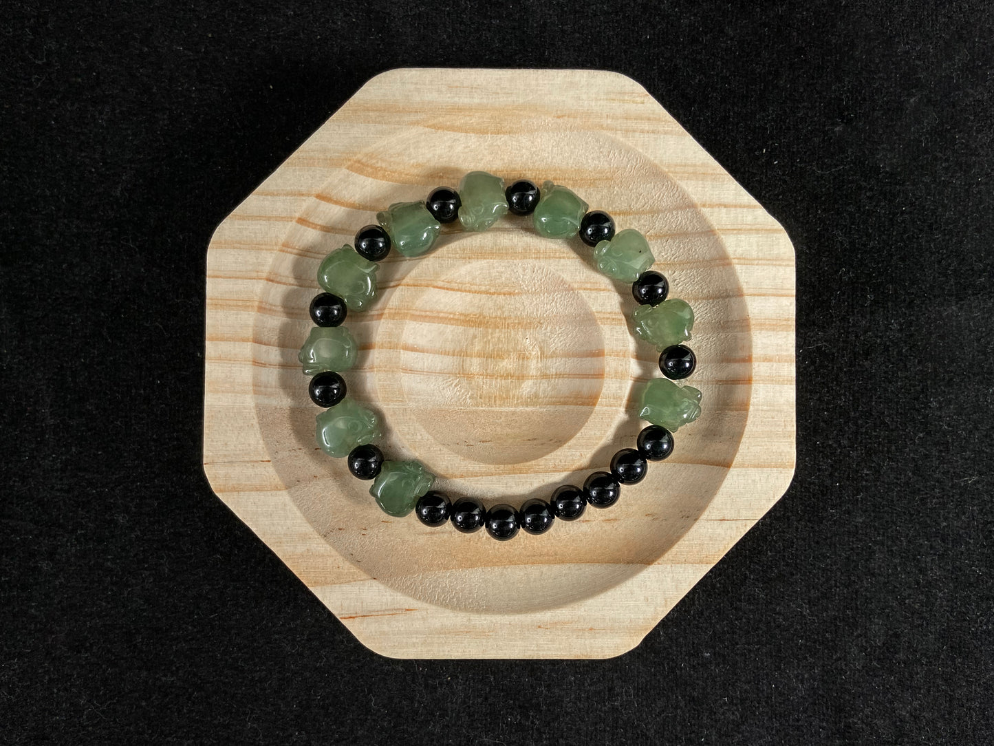 A jade bead strand featuring 17 black beads and 10 light green pig shaped beads.