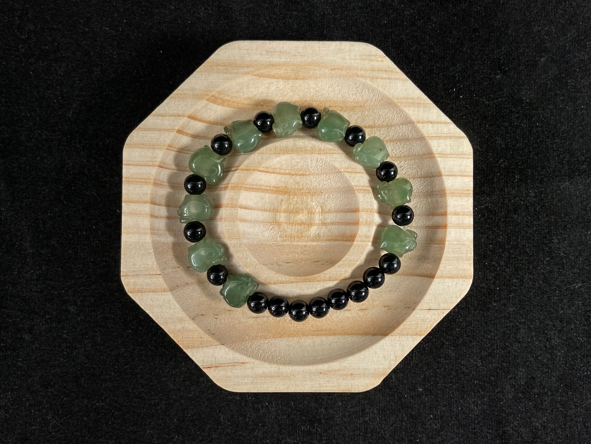 A jade bead strand featuring 17 black beads and 10 light green pig shaped beads.