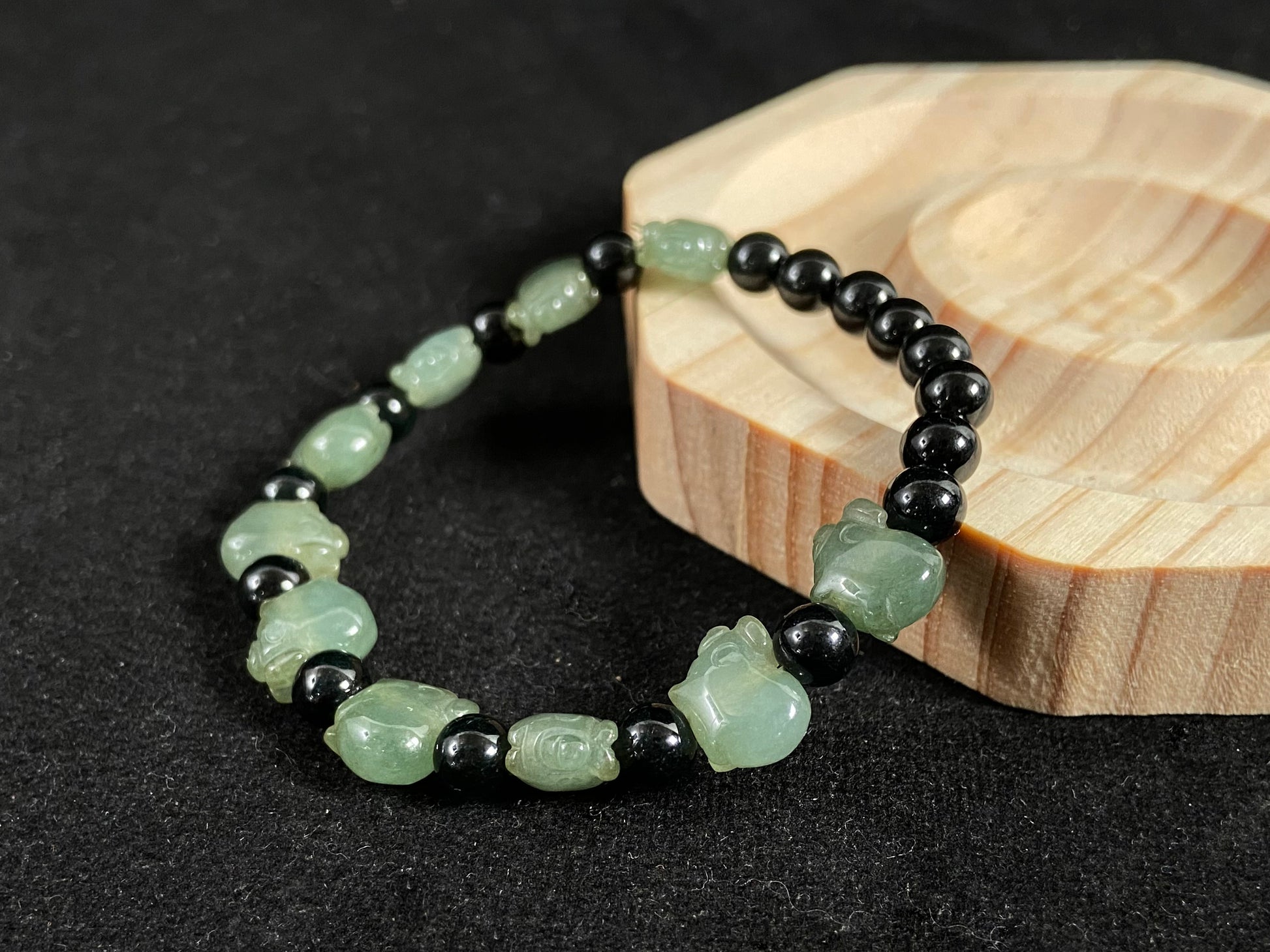 A jade bead strand featuring 17 black beads and 10 light green pig shaped beads.
