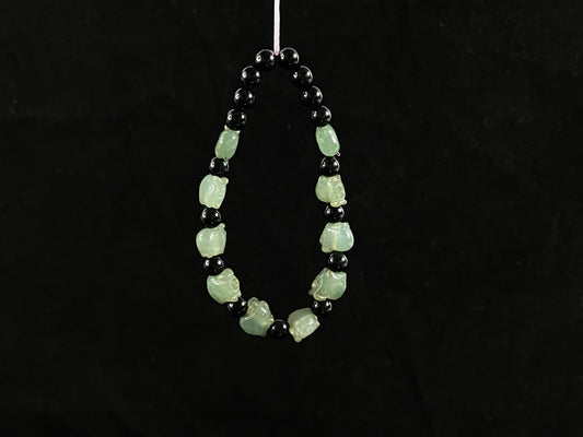 A jade bead strand featuring 17 black beads and 10 light green pig shaped beads.