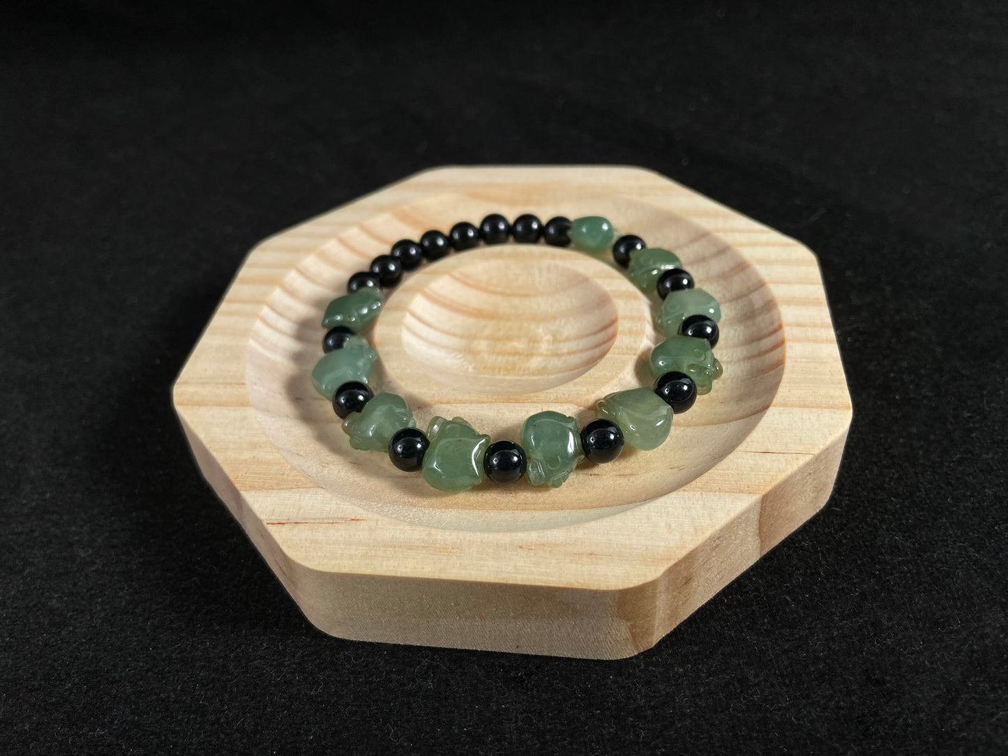 A jade bead strand featuring 17 black beads and 10 light green pig shaped beads.