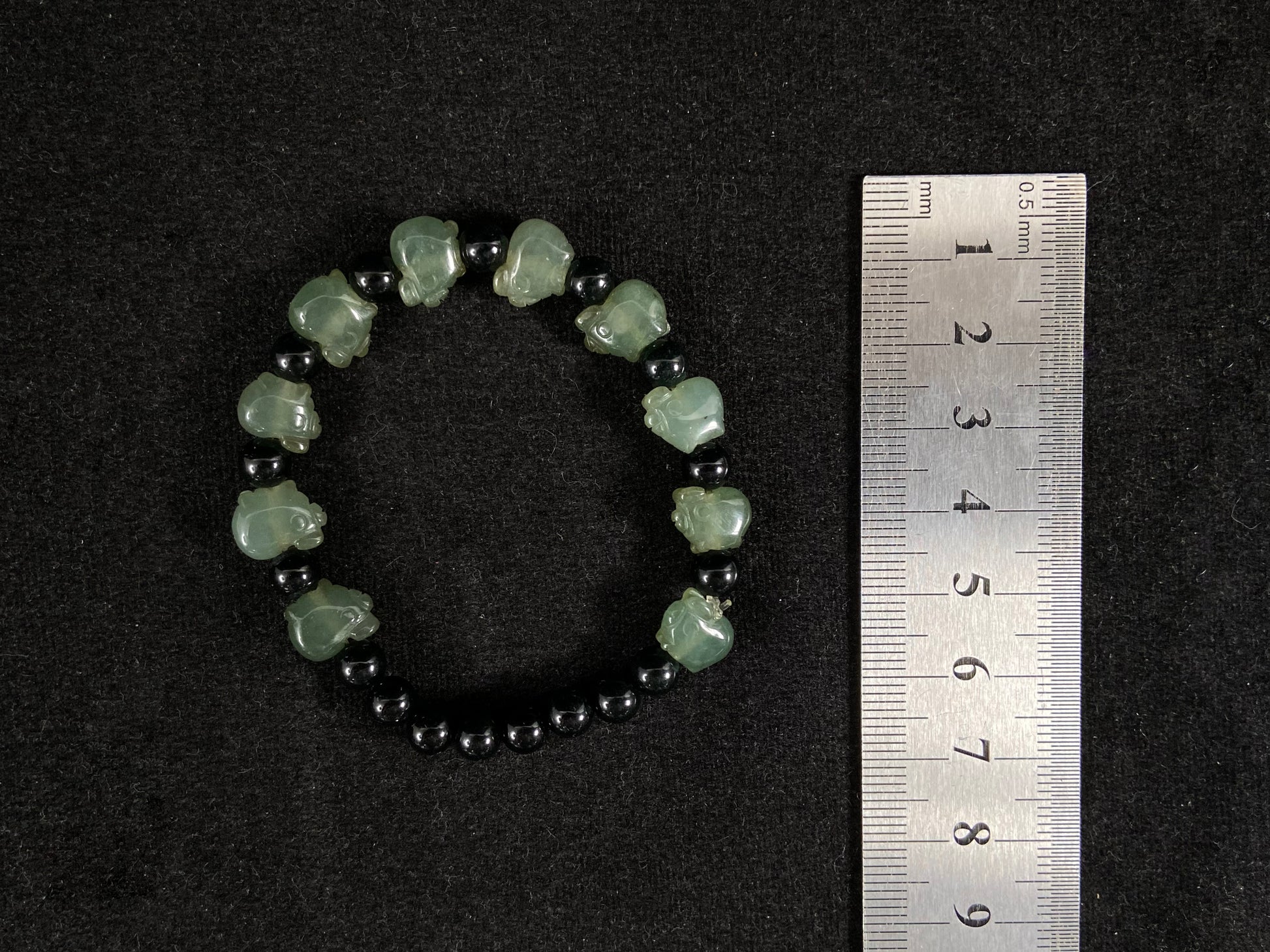 A jade bead strand featuring 17 black beads and 10 light green pig shaped beads.