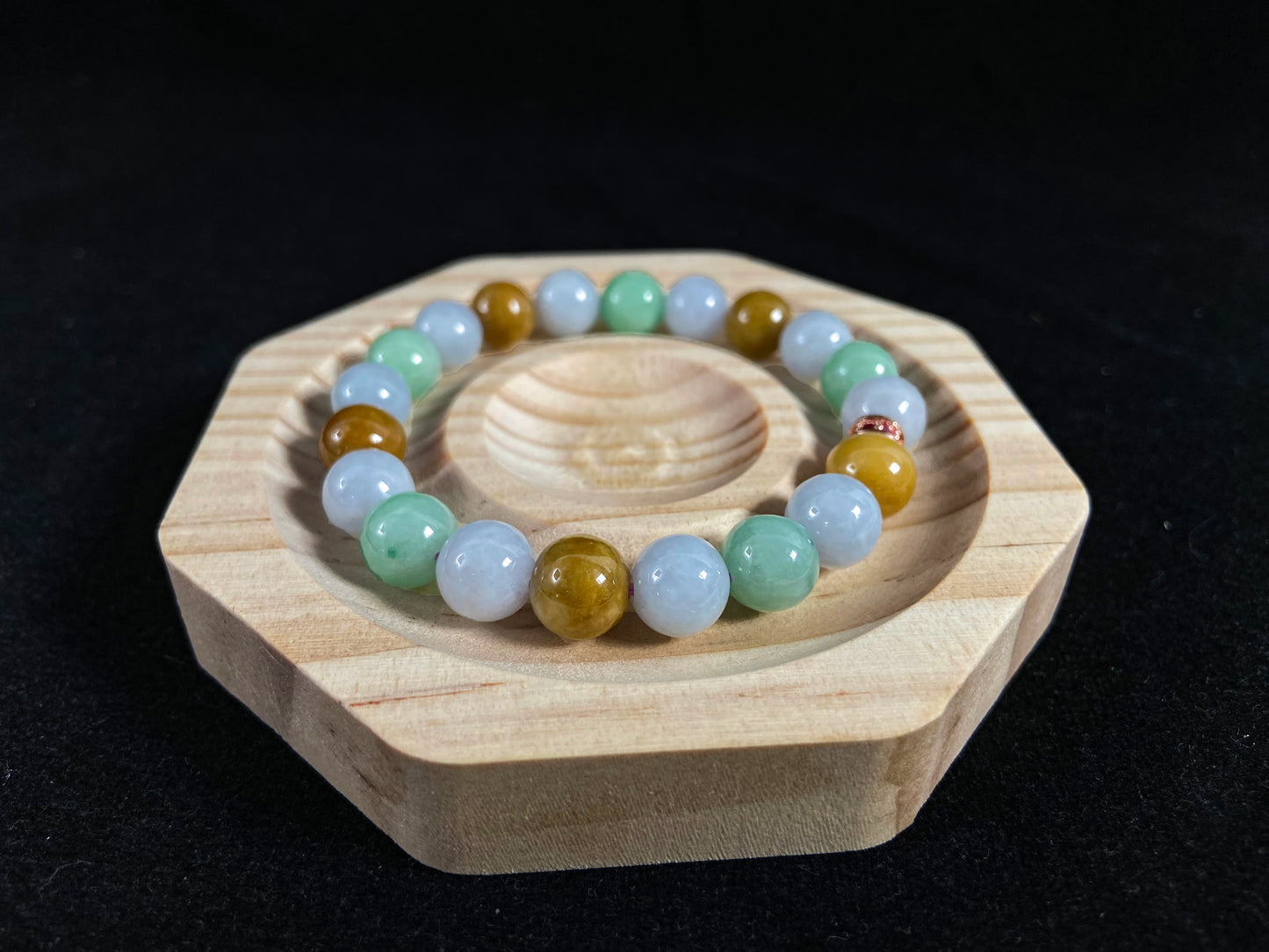 A jade bead strand combining yellow, brown, creamy white, and light green beads, accented with a rose gold alloy cylinder.