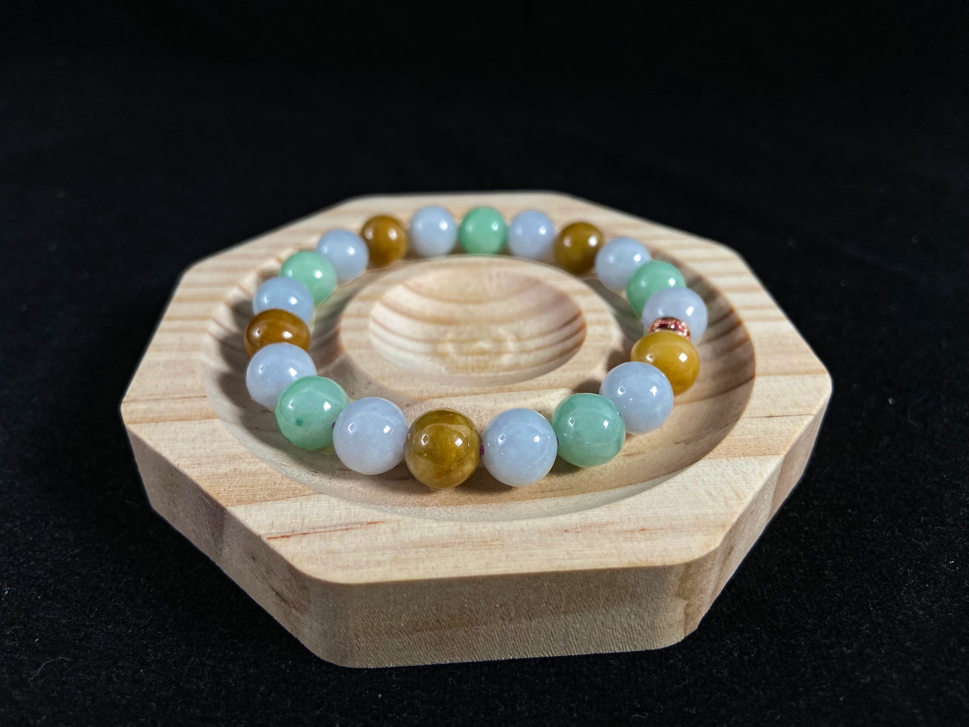 A jade bead strand combining yellow, brown, creamy white, and light green beads, accented with a rose gold alloy cylinder.