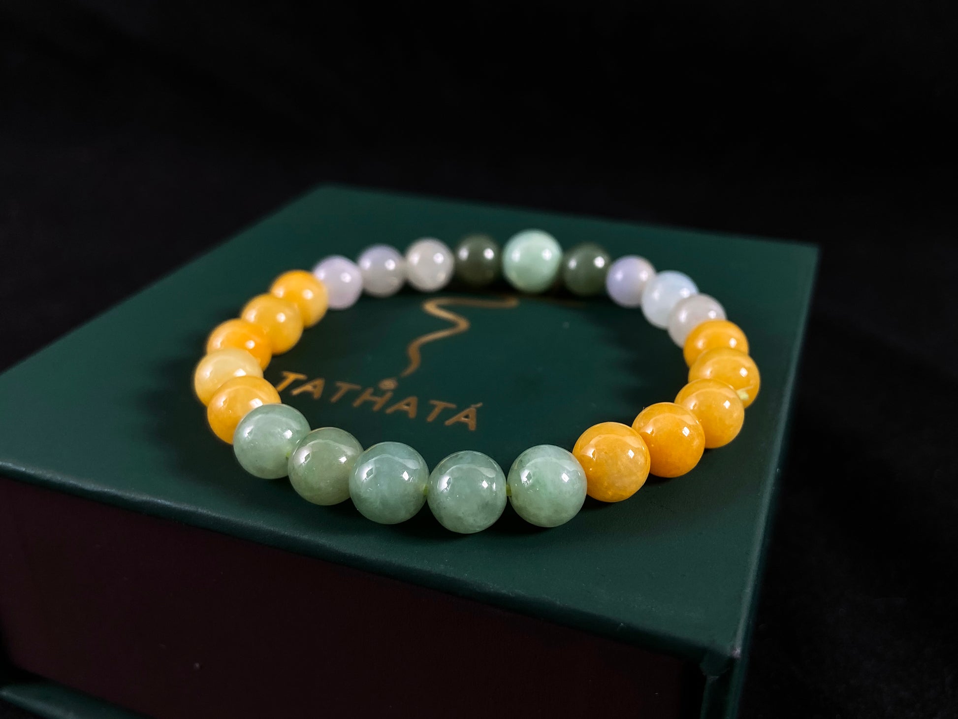 A jade bead strand featuring yellow, deep green, light green, and white-purple beads.