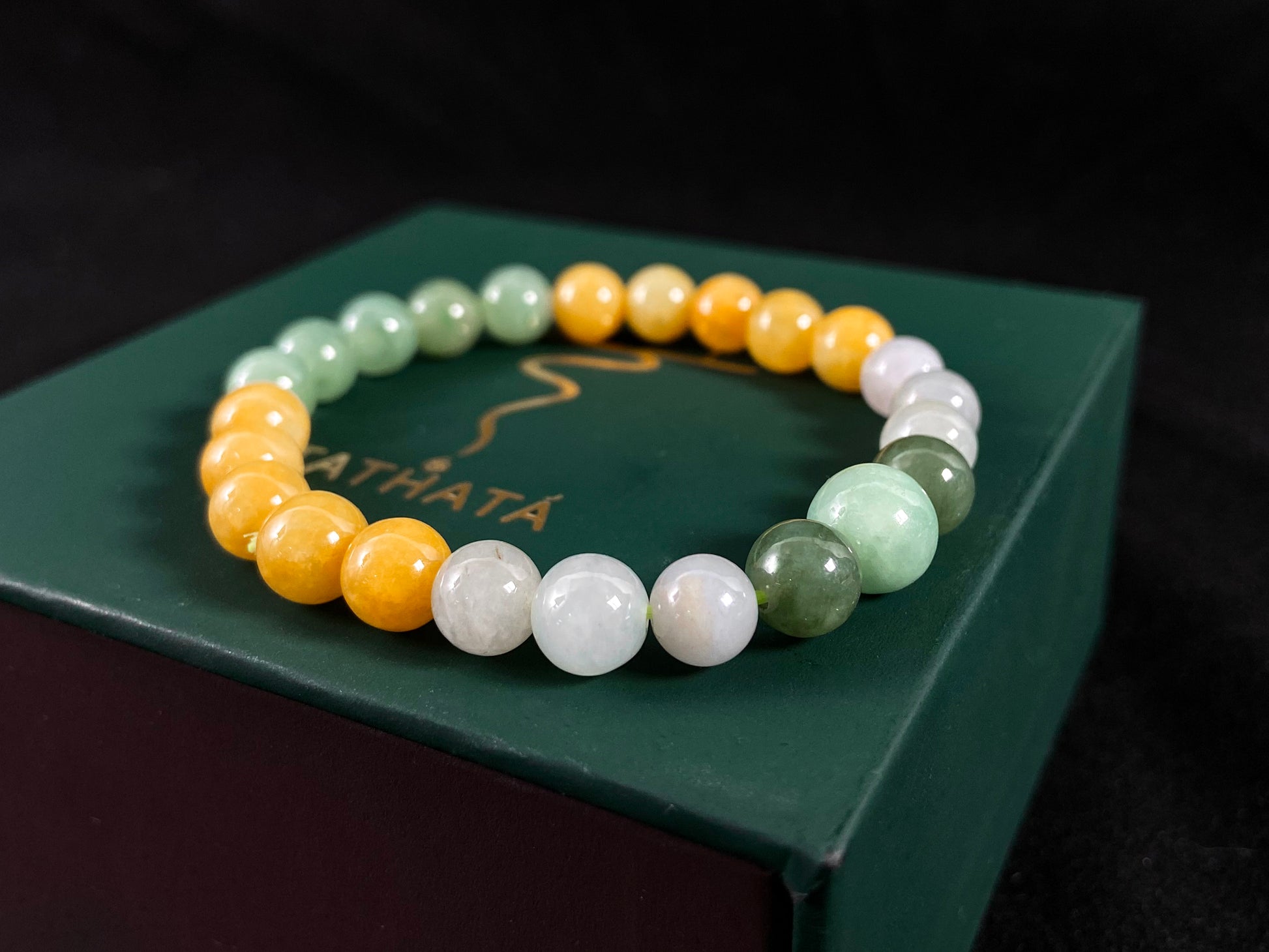 A jade bead strand featuring yellow, deep green, light green, and white-purple beads.