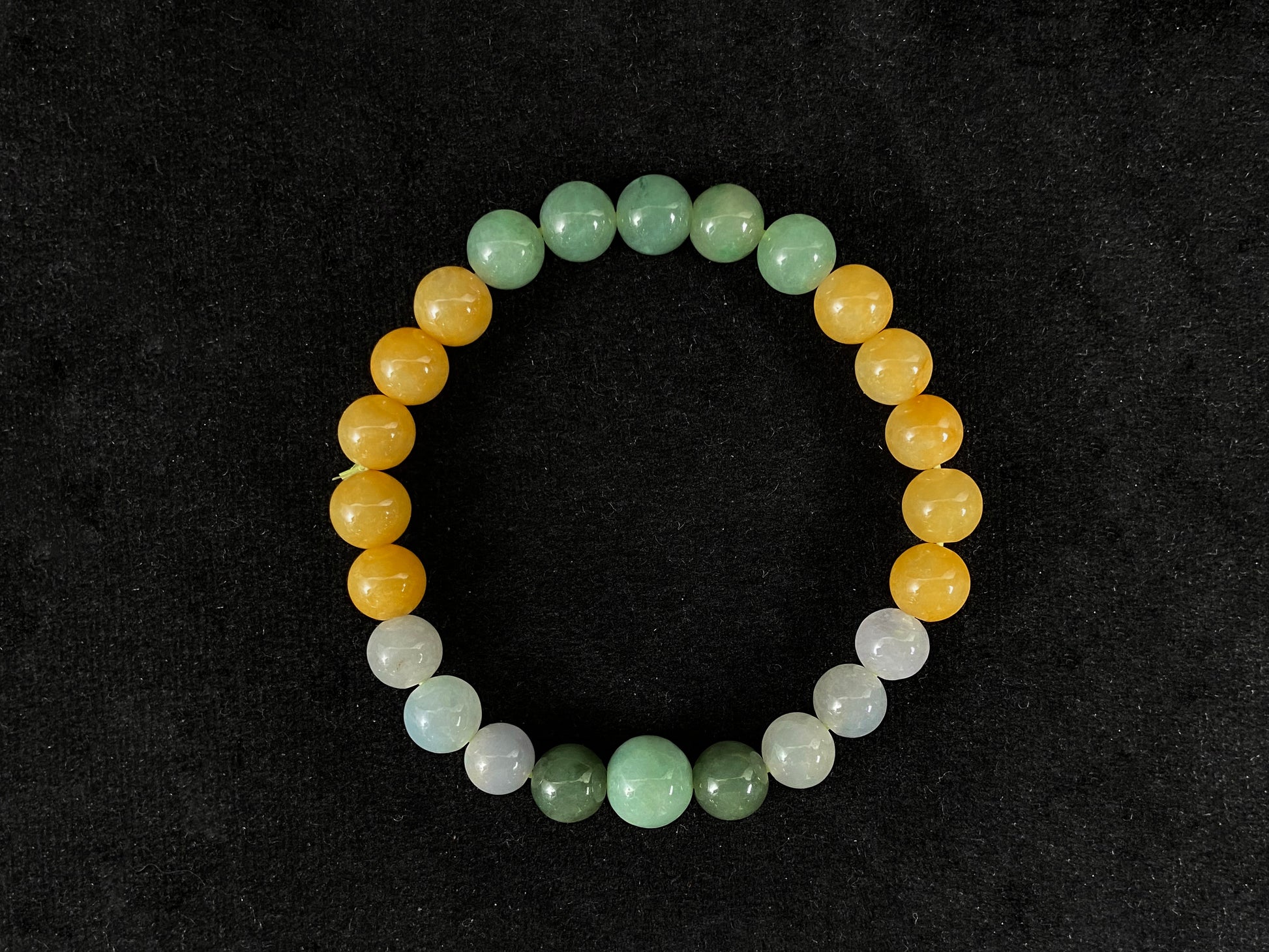 A jade bead strand featuring yellow, deep green, light green, and white-purple beads.