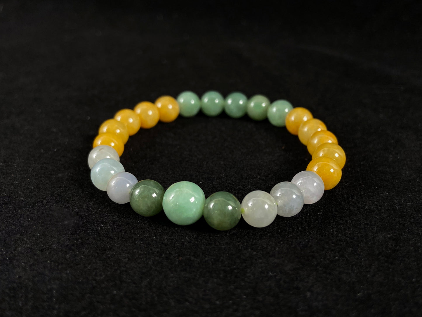 A jade bead strand featuring yellow, deep green, light green, and white-purple beads.