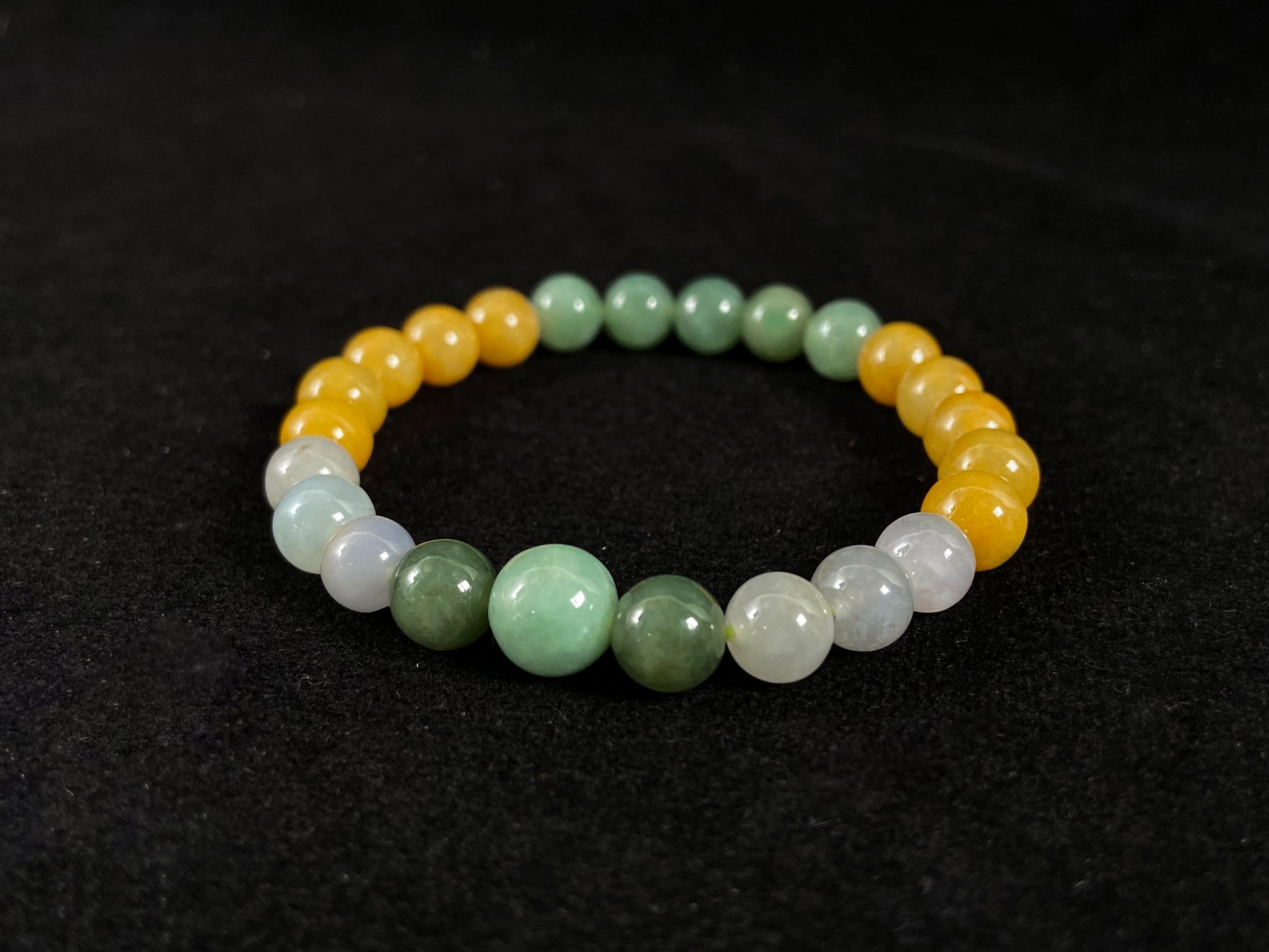 A jade bead strand featuring yellow, deep green, light green, and white-purple beads.