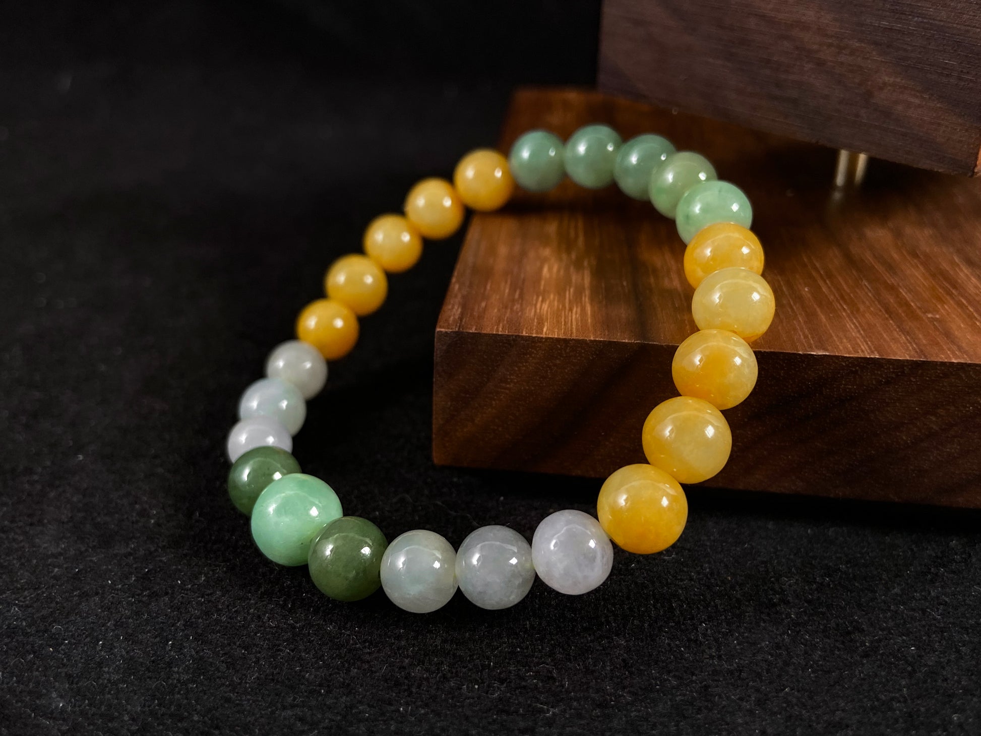 A jade bead strand featuring yellow, deep green, light green, and white-purple beads.