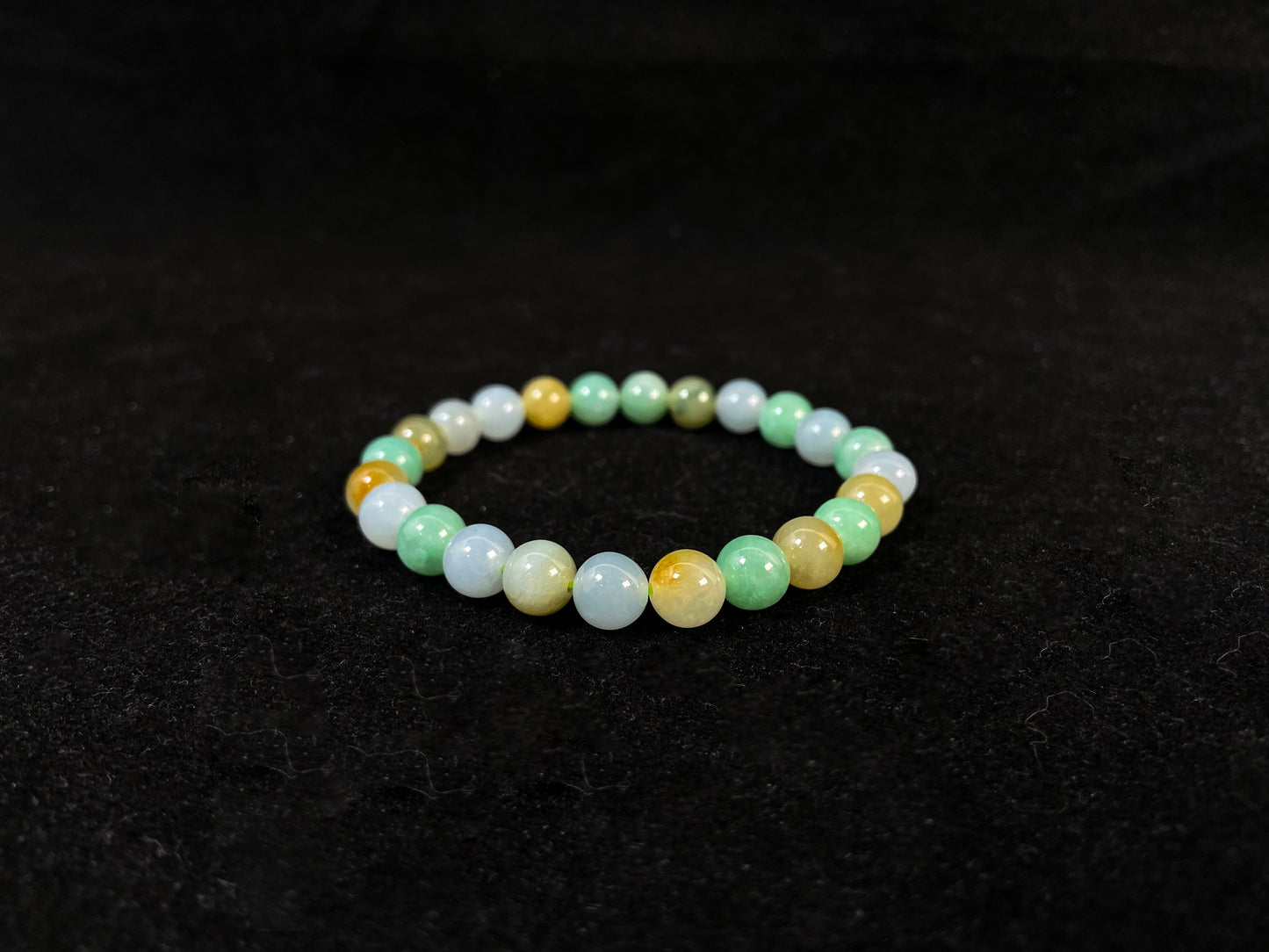 A jade bead strand featuring apple green, yellow, brown, and icy white hues.