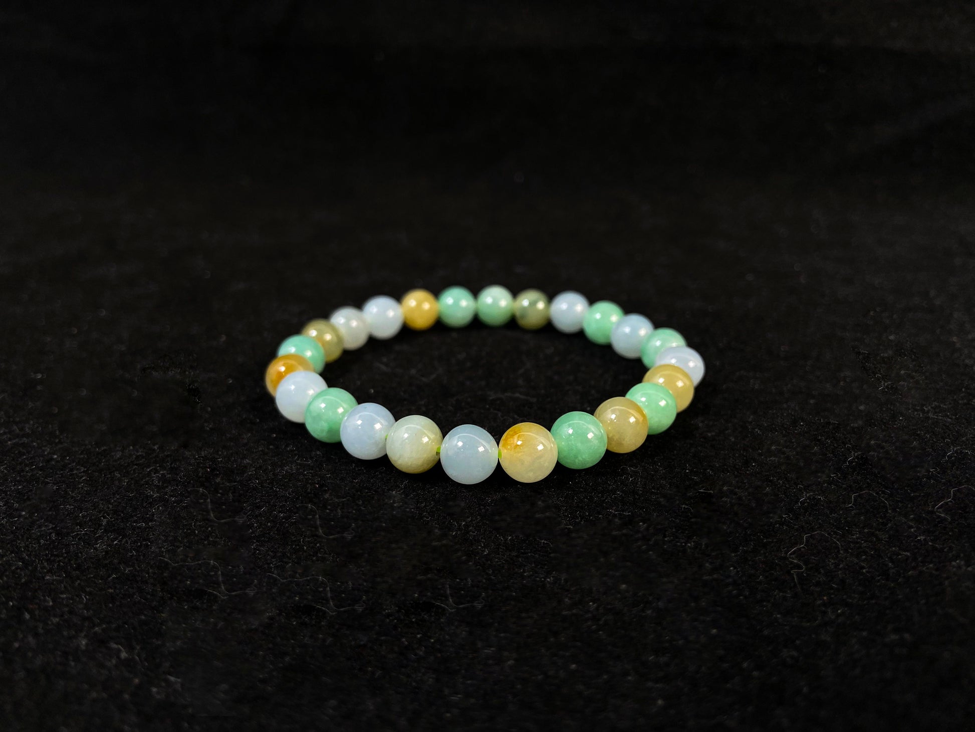 A jade bead strand featuring apple green, yellow, brown, and icy white hues.