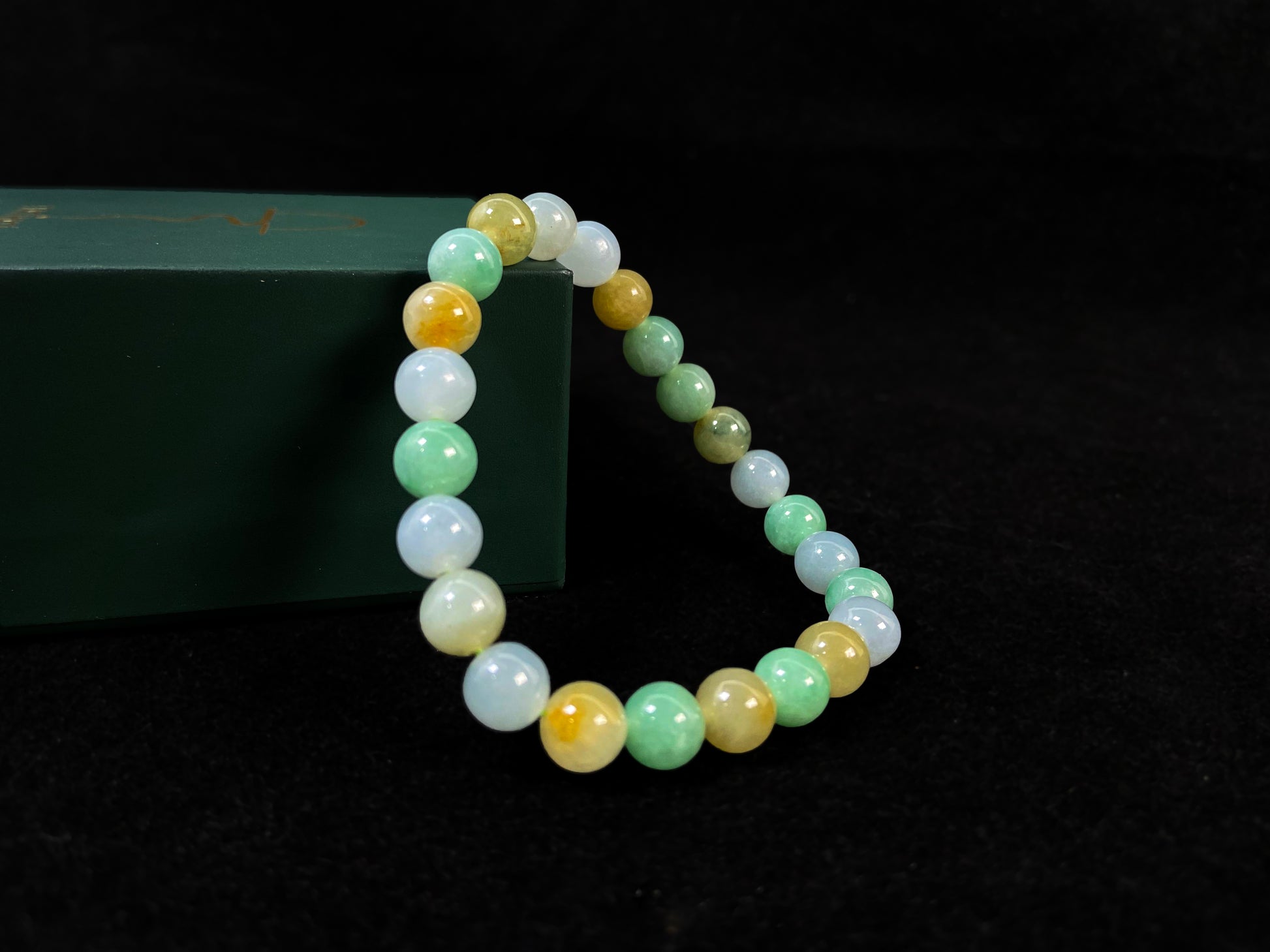 A jade bead strand featuring apple green, yellow, brown, and icy white hues.