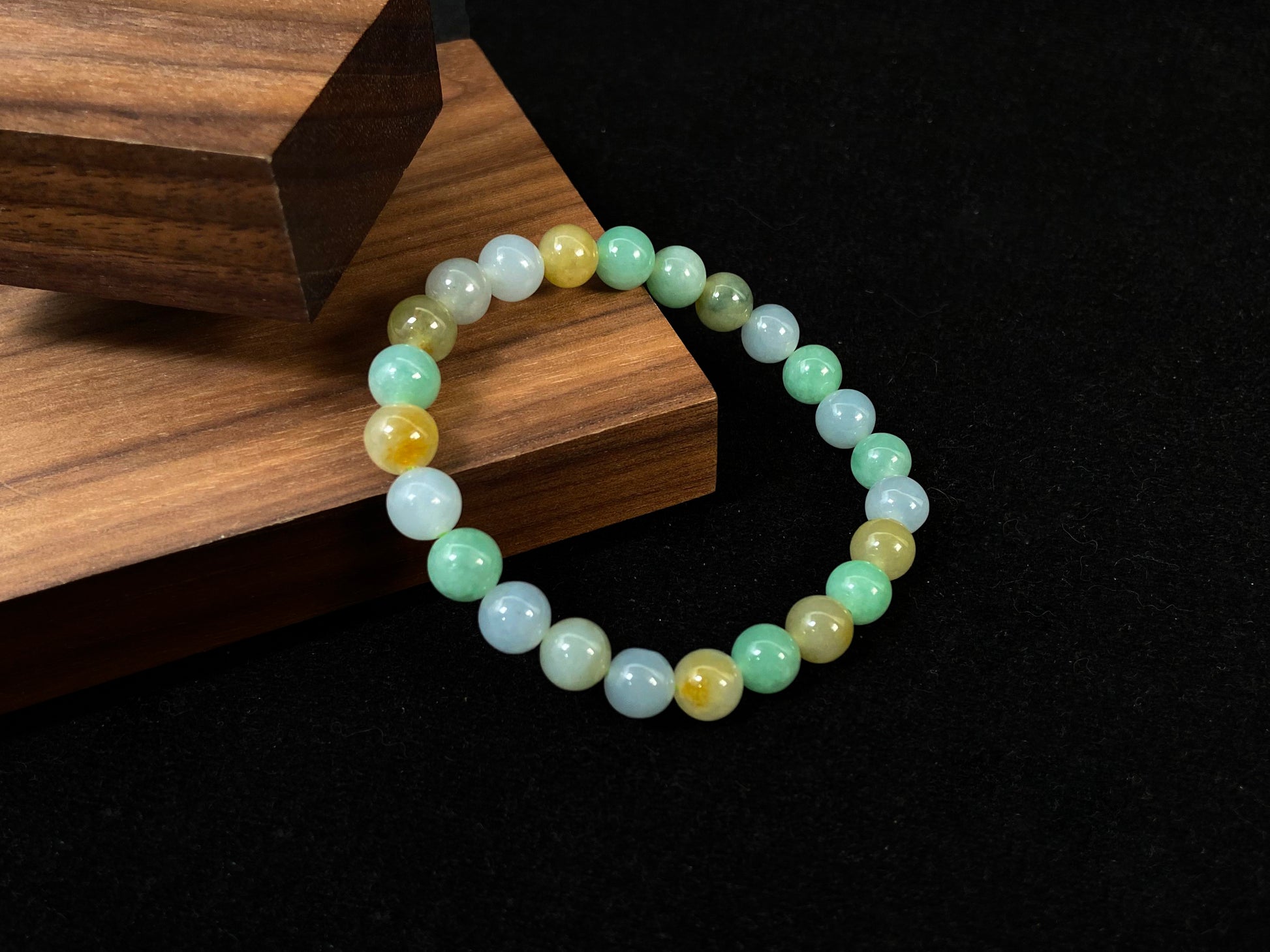 A jade bead strand featuring apple green, yellow, brown, and icy white hues.