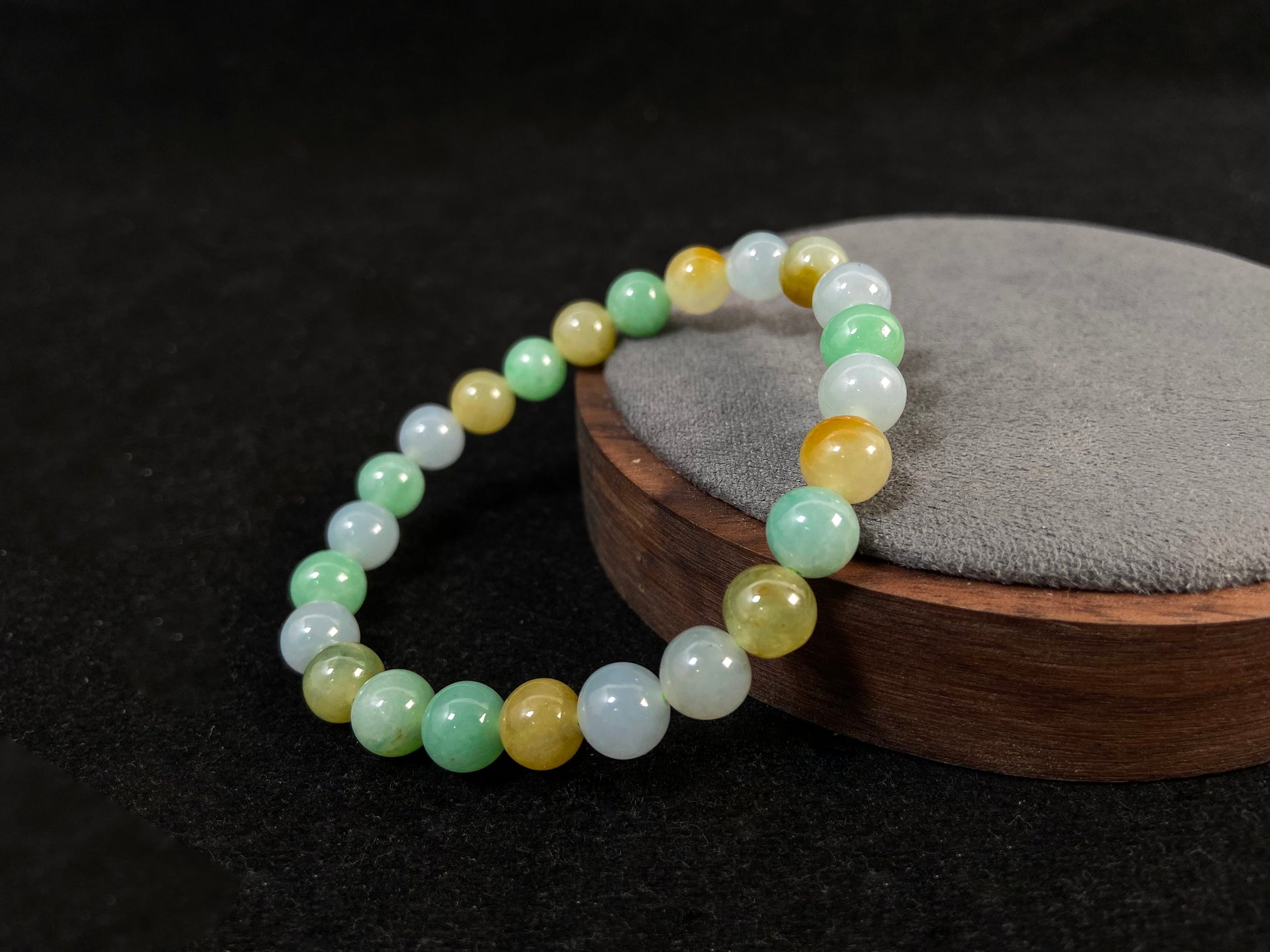A jade bead strand featuring apple green, yellow, brown, and icy white hues.