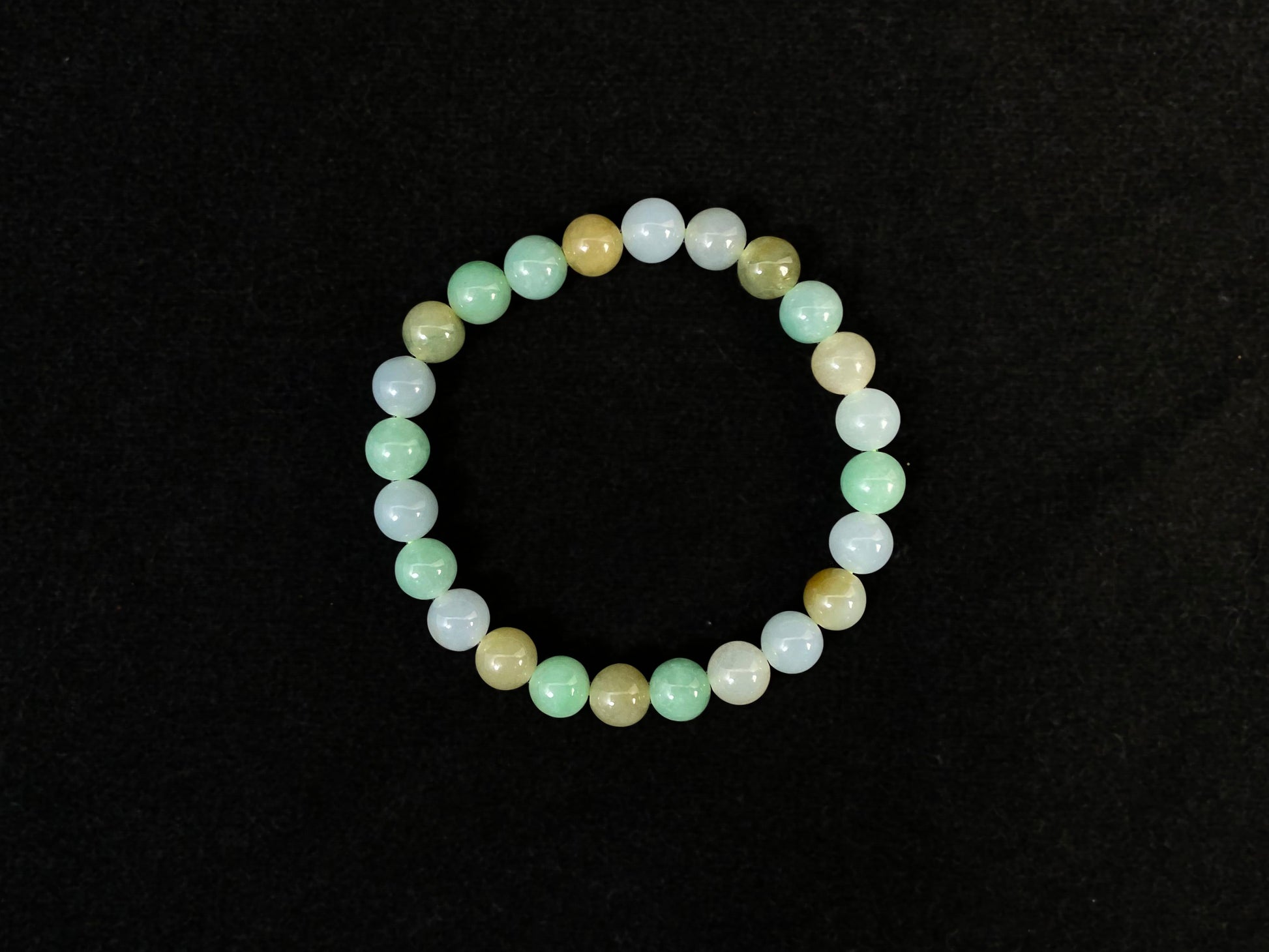 A jade bead strand featuring apple green, yellow, brown, and icy white hues.