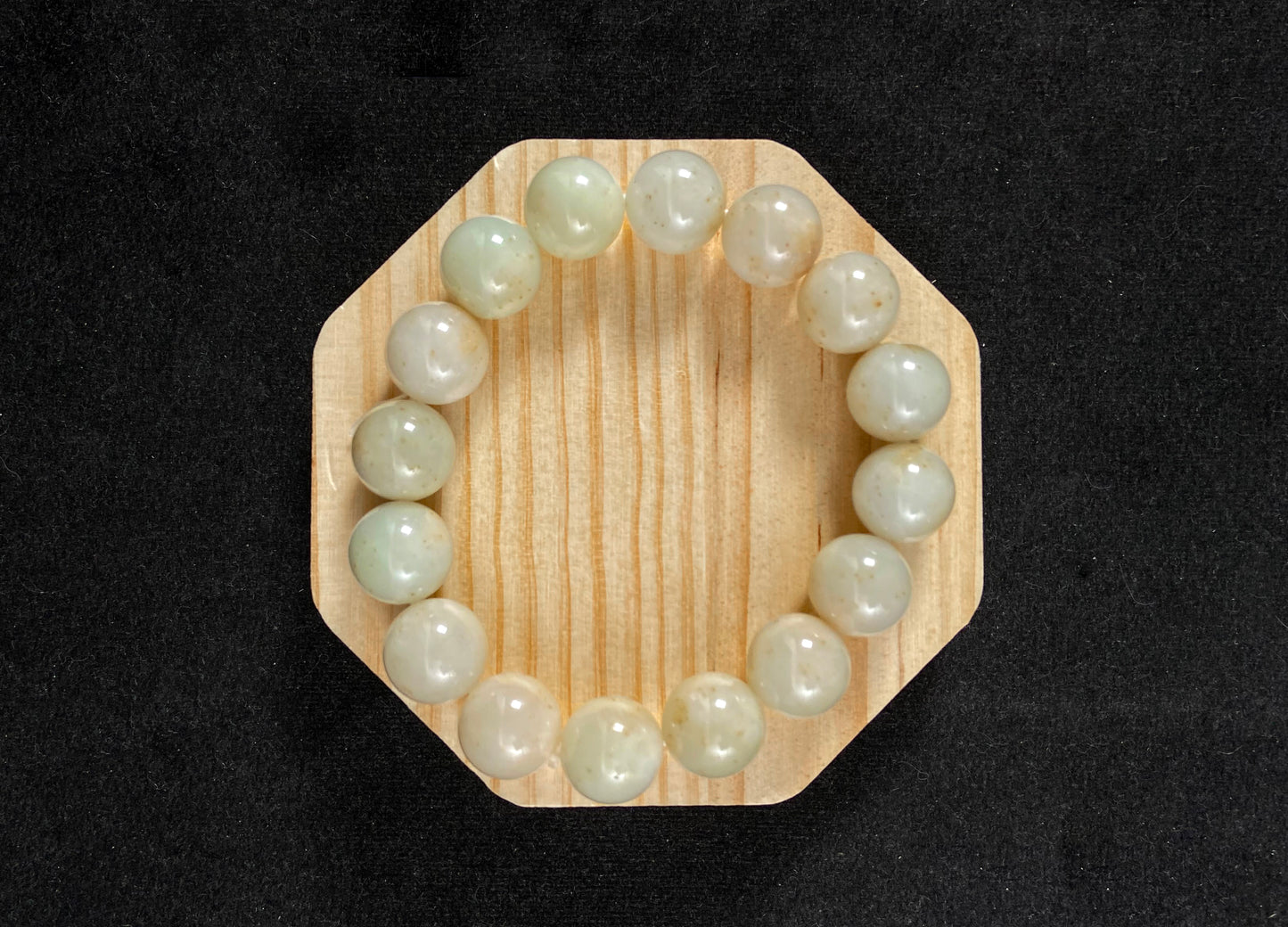 A strand of beige jade beads delicately adorned with golden speckles.
