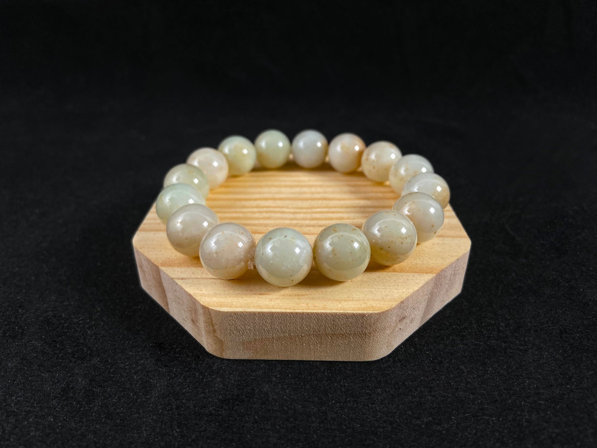A strand of beige jade beads delicately adorned with golden speckles.