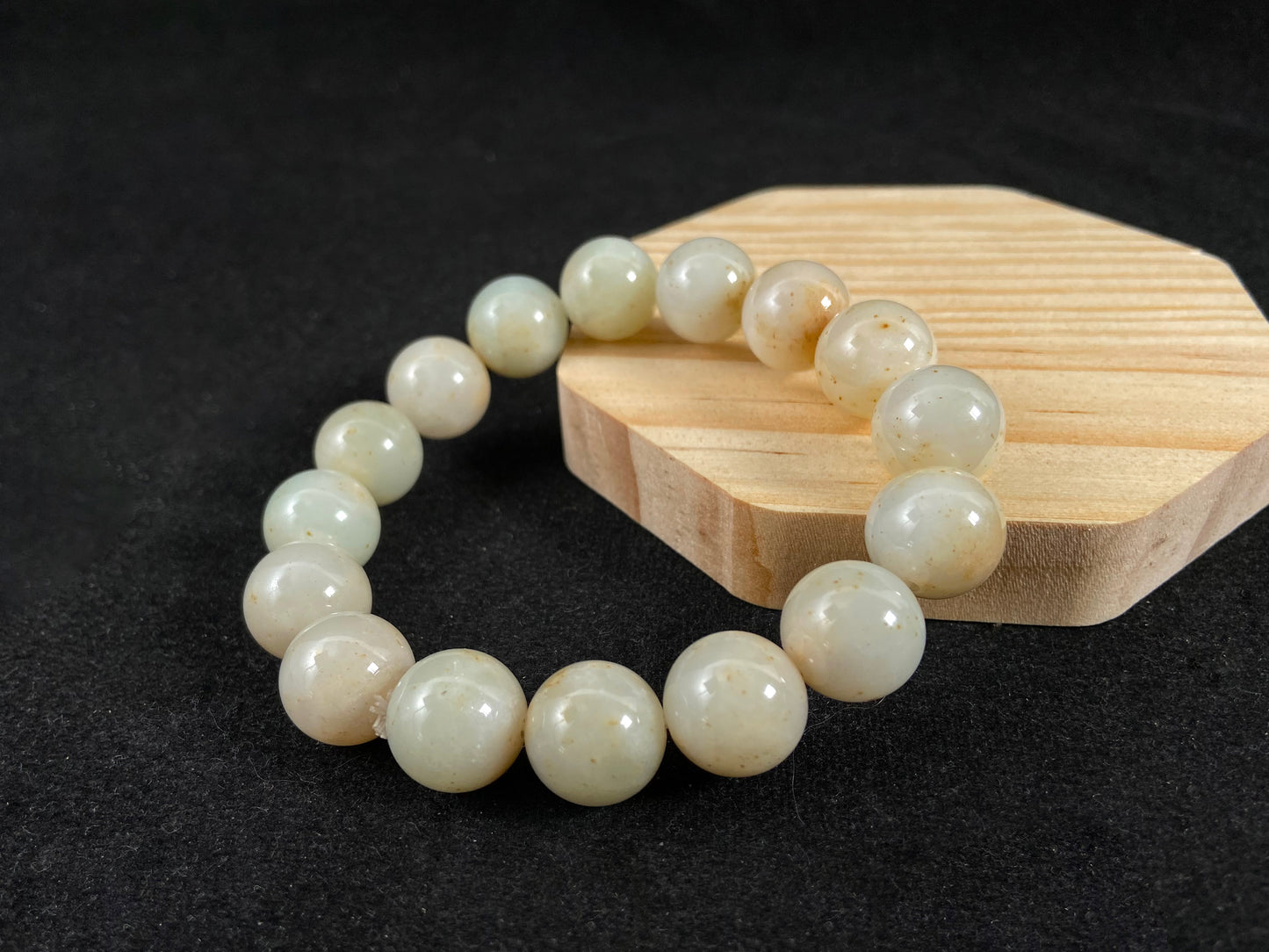 A strand of beige jade beads delicately adorned with golden speckles.
