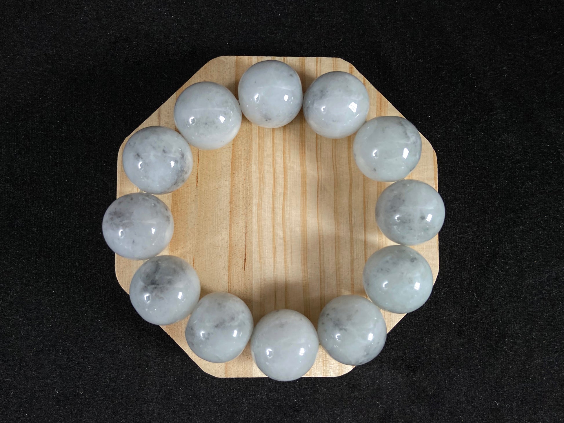 A jade bead strand featuring creamy white beads with gray speckles.