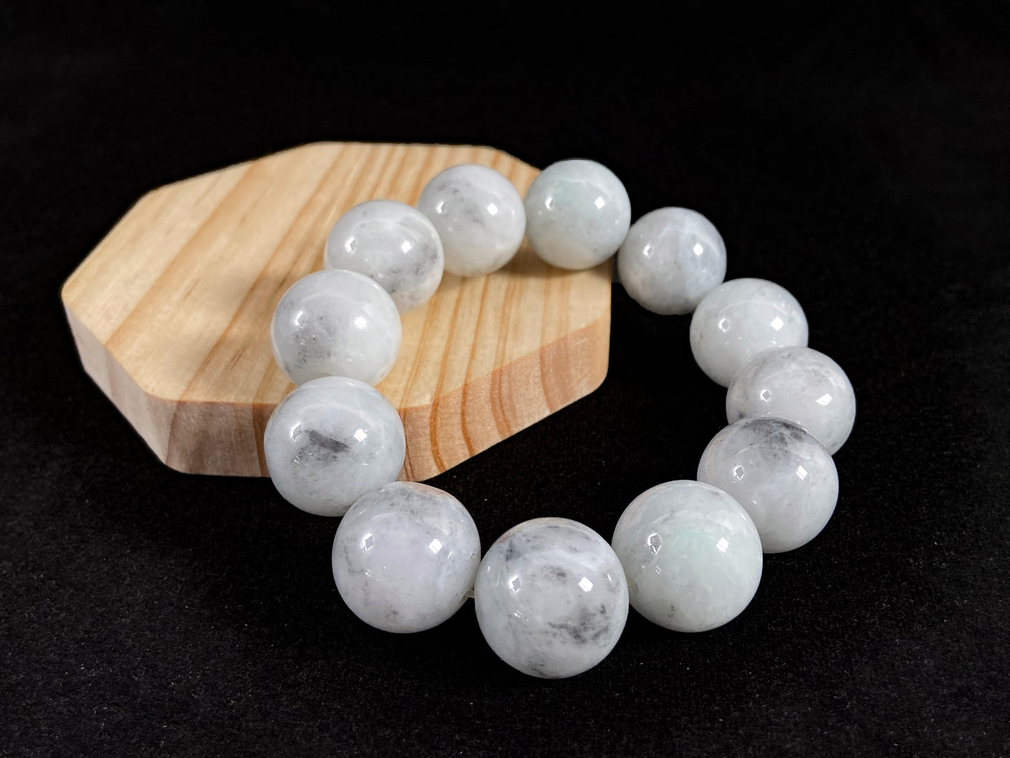 A jade bead strand featuring creamy white beads with gray speckles.
