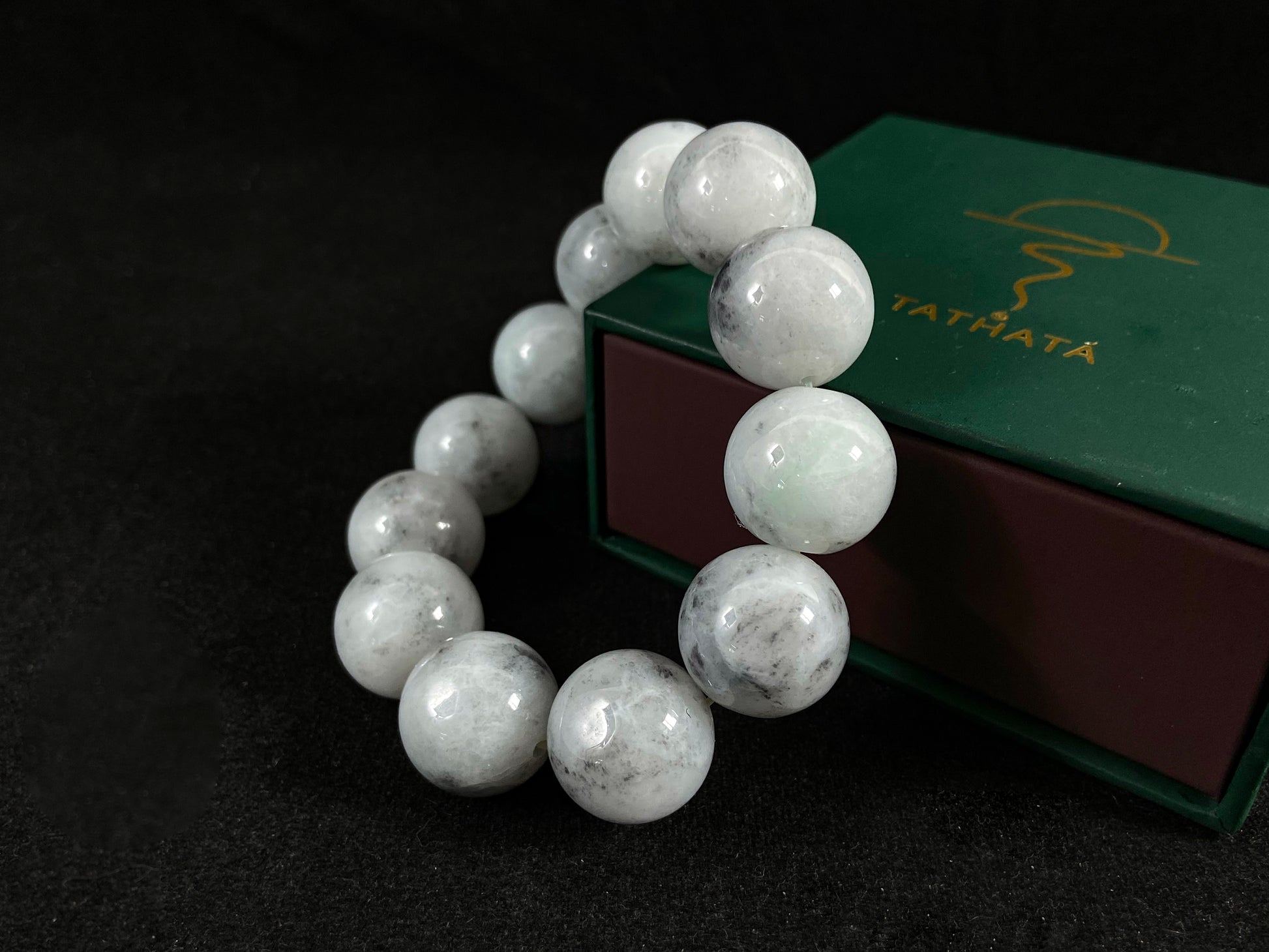 A jade bead strand featuring creamy white beads with gray speckles.