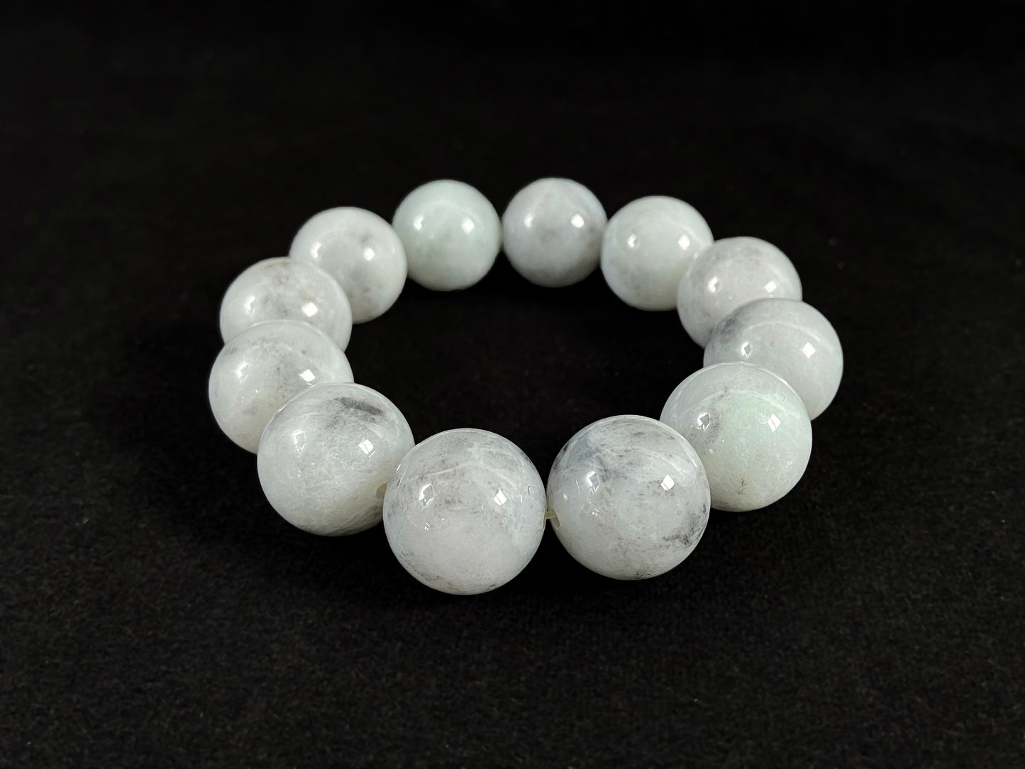 A jade bead strand featuring creamy white beads with gray speckles.