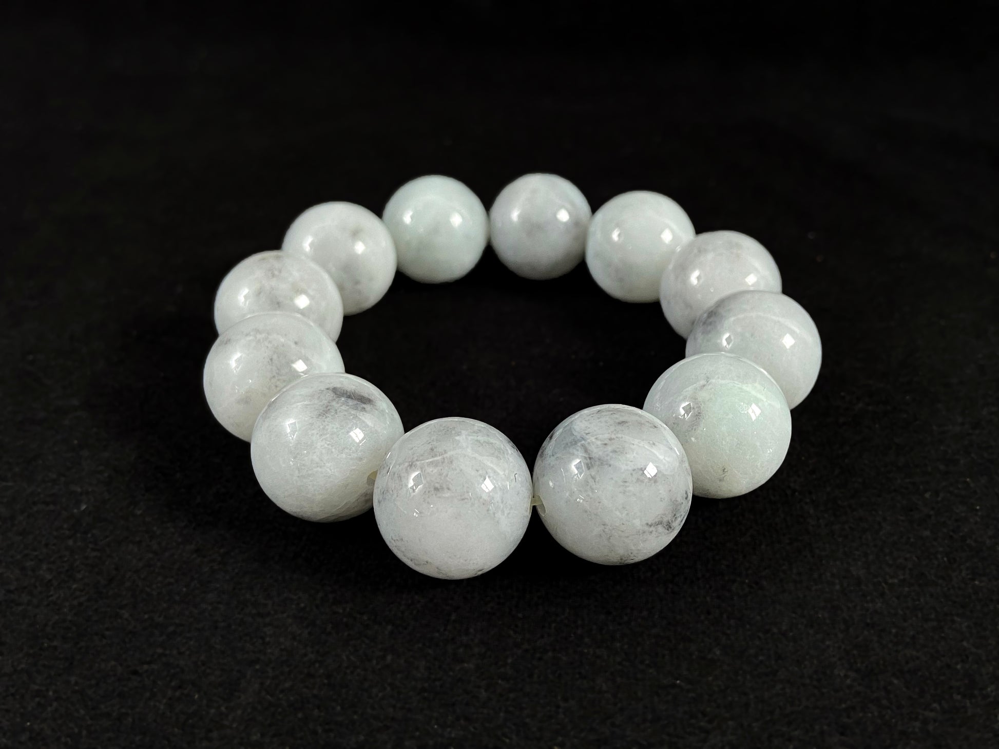 A jade bead strand featuring creamy white beads with gray speckles.