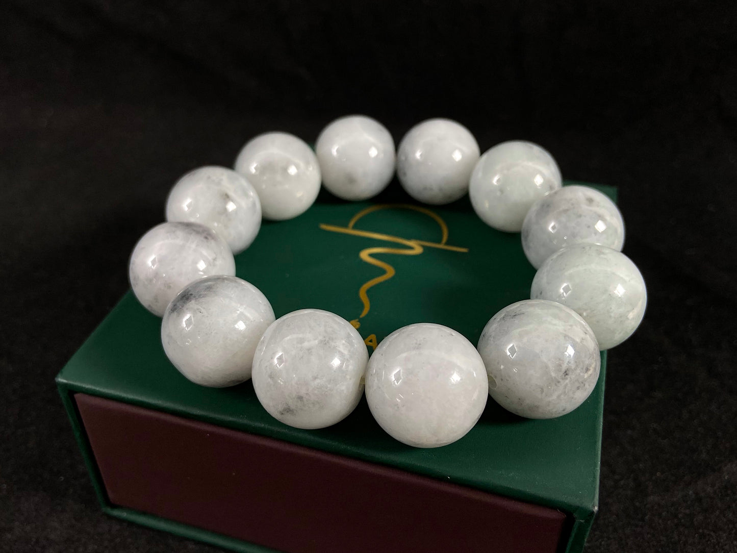 A jade bead strand featuring creamy white beads with gray speckles.