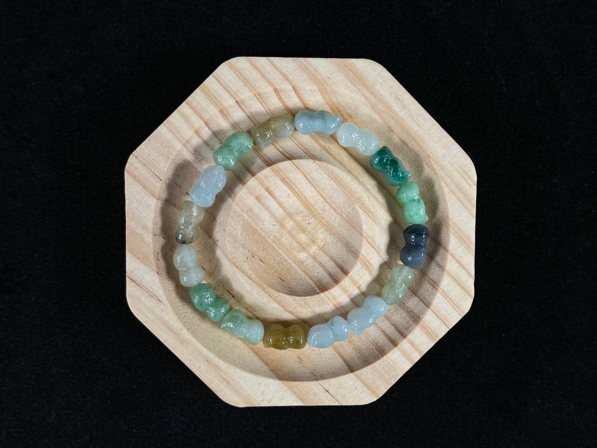 A strand of peanut shaped jade beads in soft yellow, green, brown, grey and ombre white to deep green.