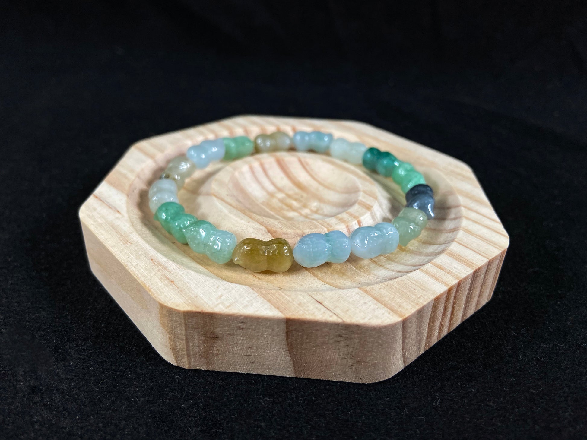 A strand of peanut shaped jade beads in soft yellow, green, brown, grey and ombre white to deep green.