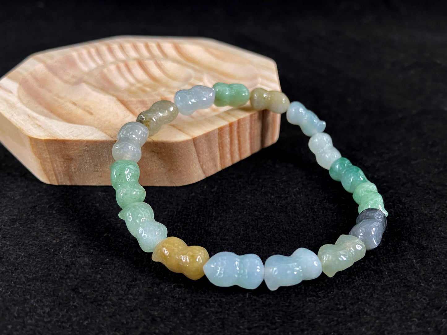 A strand of peanut shaped jade beads in soft yellow, green, brown, grey and ombre white to deep green.