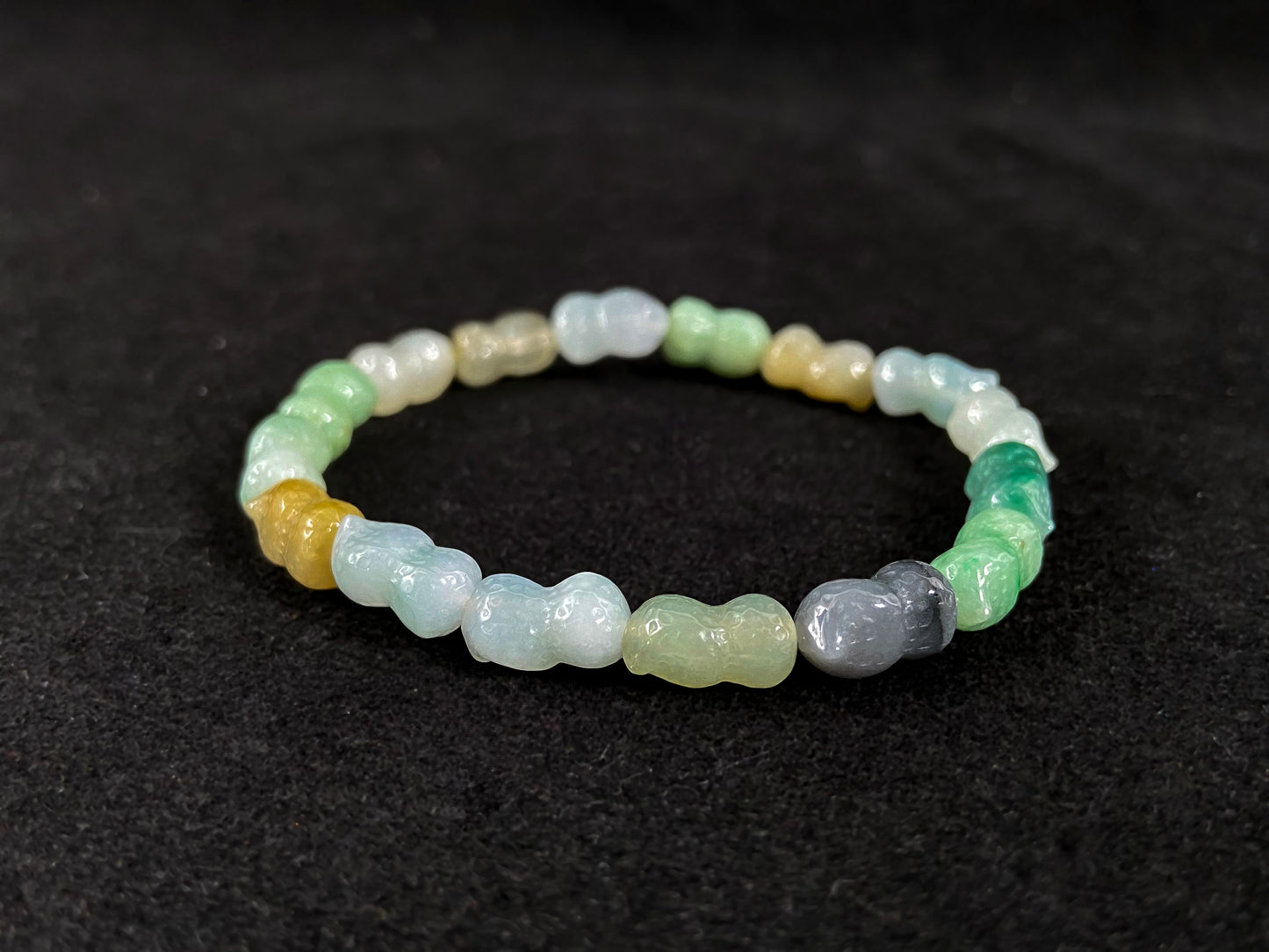 A strand of peanut shaped jade beads in soft yellow, green, brown, grey and ombre white to deep green.