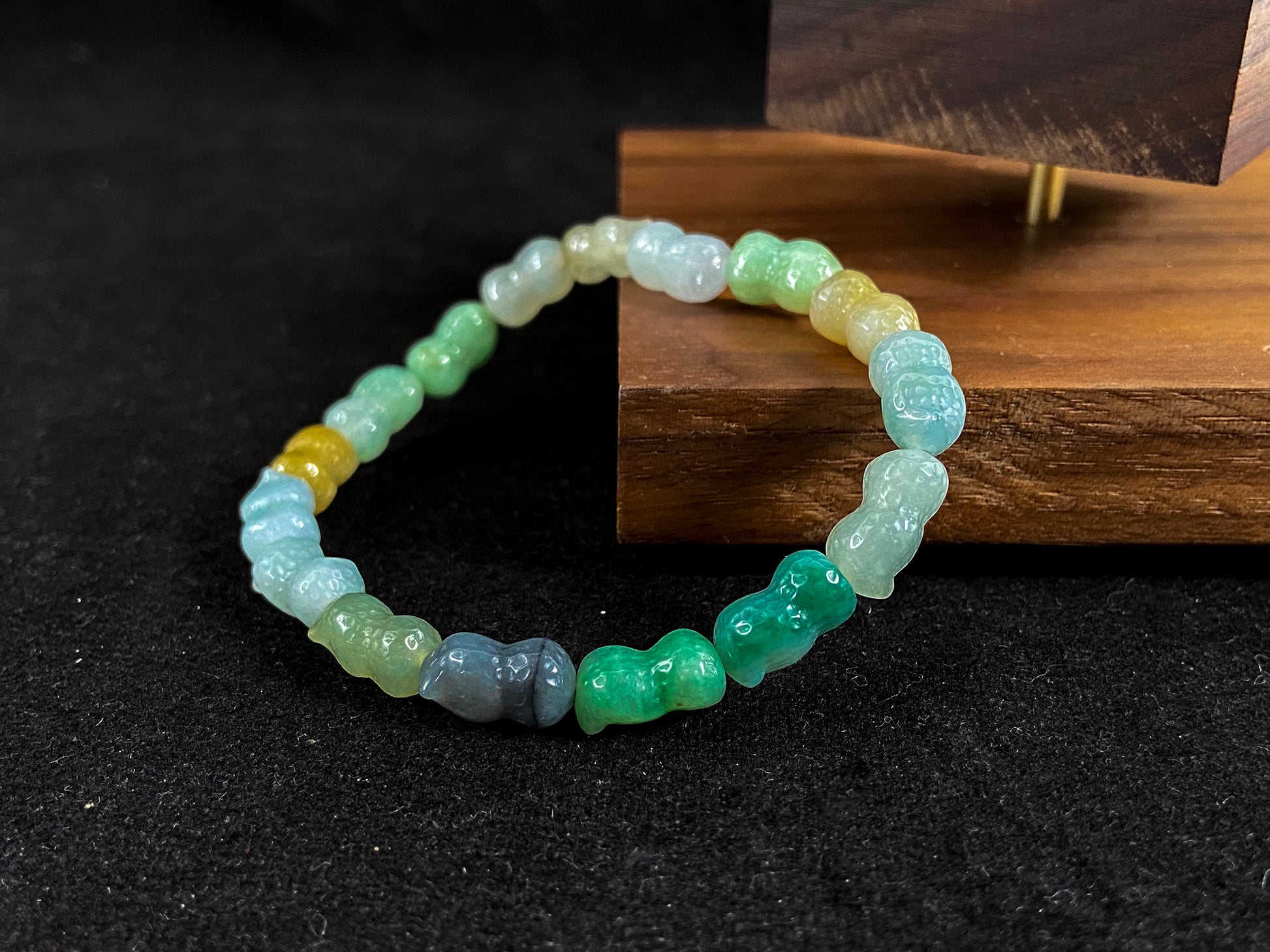 A strand of peanut shaped jade beads in soft yellow, green, brown, grey and ombre white to deep green.